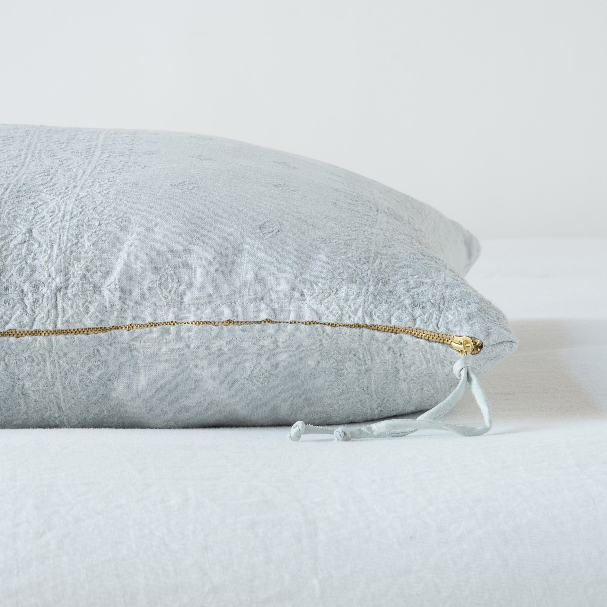 Cloud: Close-up of brass zipper and charmeuse pull details on throw pillow - side view.