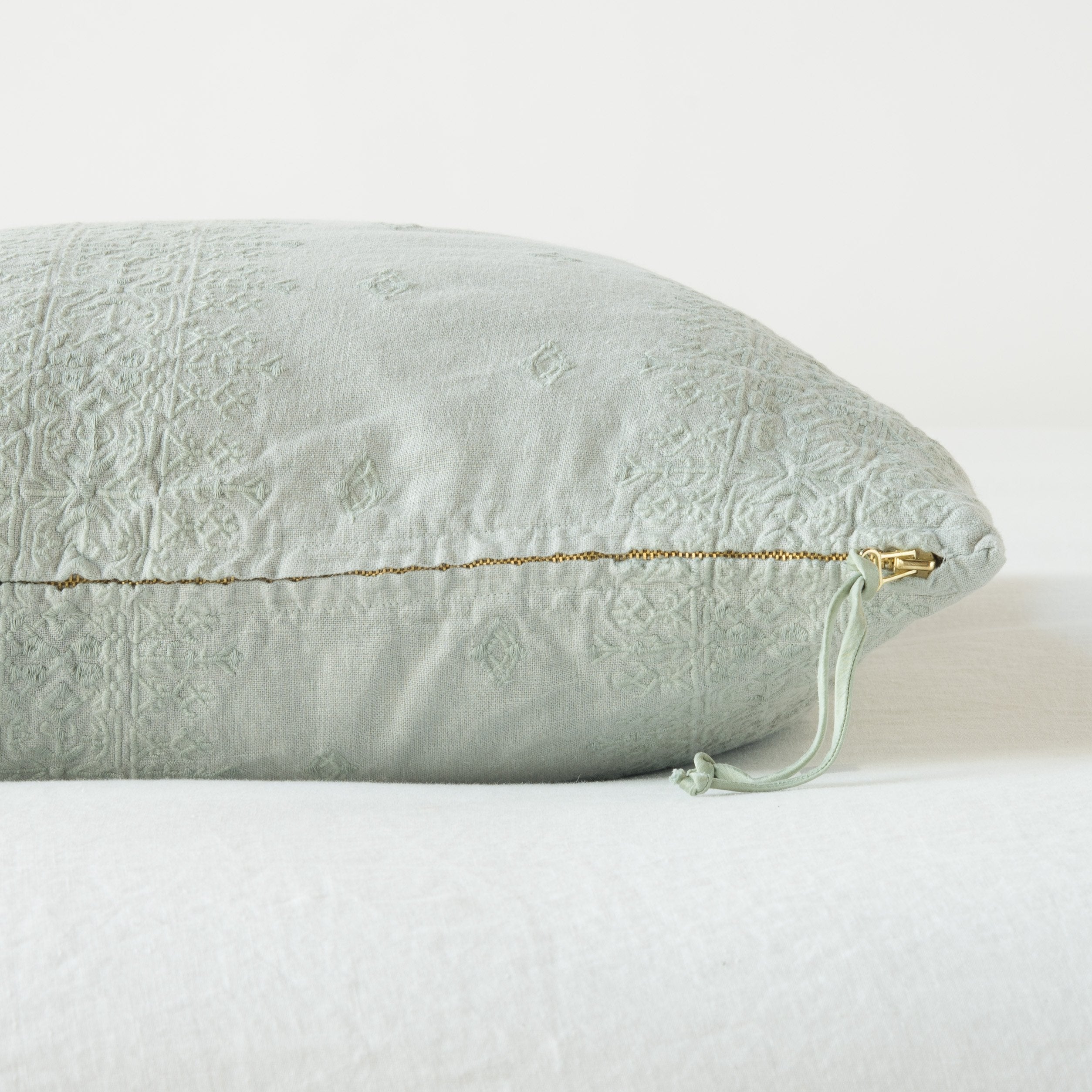 Eucalyptus: Close-up of brass zipper and charmeuse pull details in Eucalyptus Ines throw pillow - side view.
