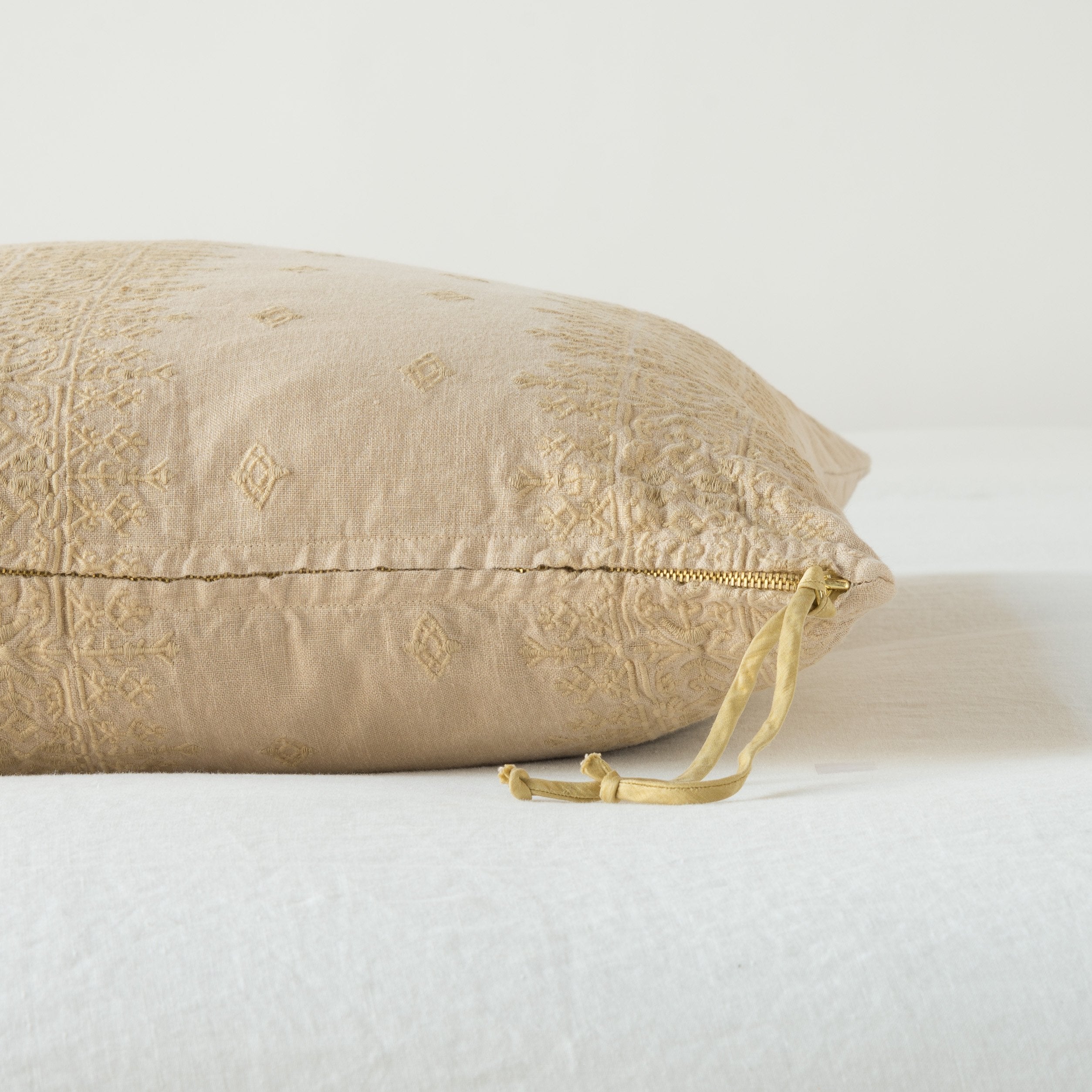 Honeycomb: Close-up of brass zipper and charmeuse pull details on throw pillow - side view.