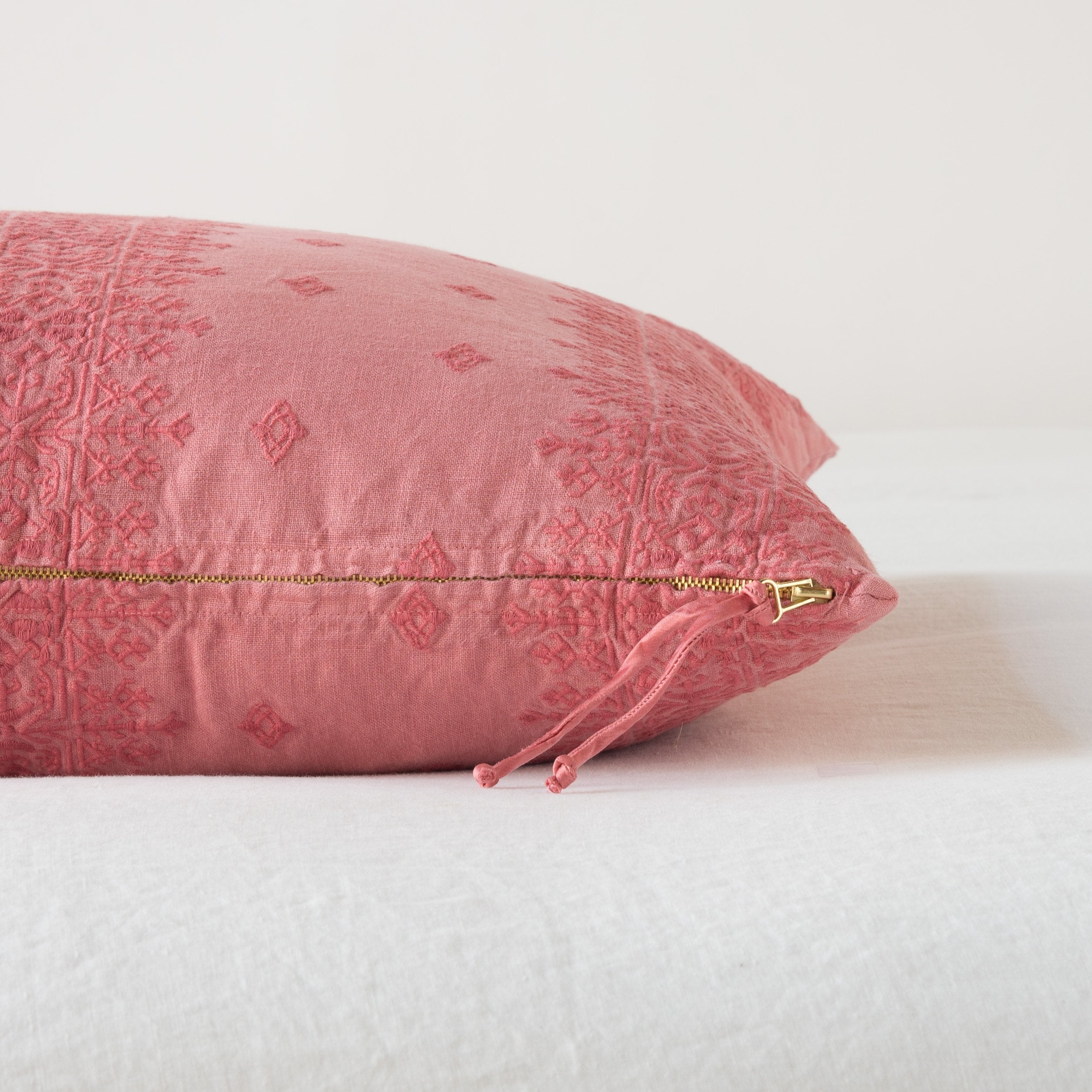 Poppy: Close-up of brass zipper and charmeuse pull details on throw pillow - side view.