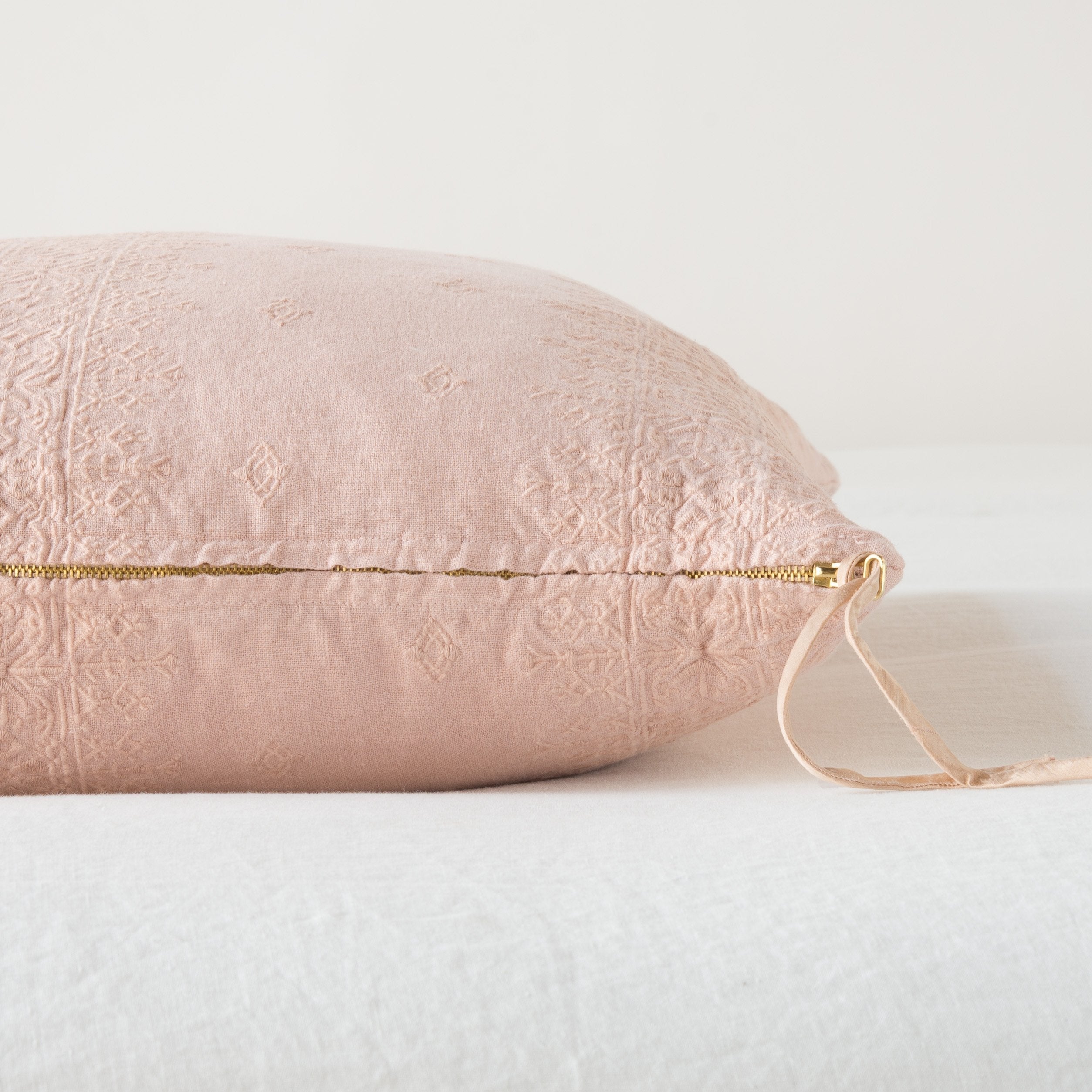 Rouge: Close-up of brass zipper and charmeuse pull details on throw pillow - side view.