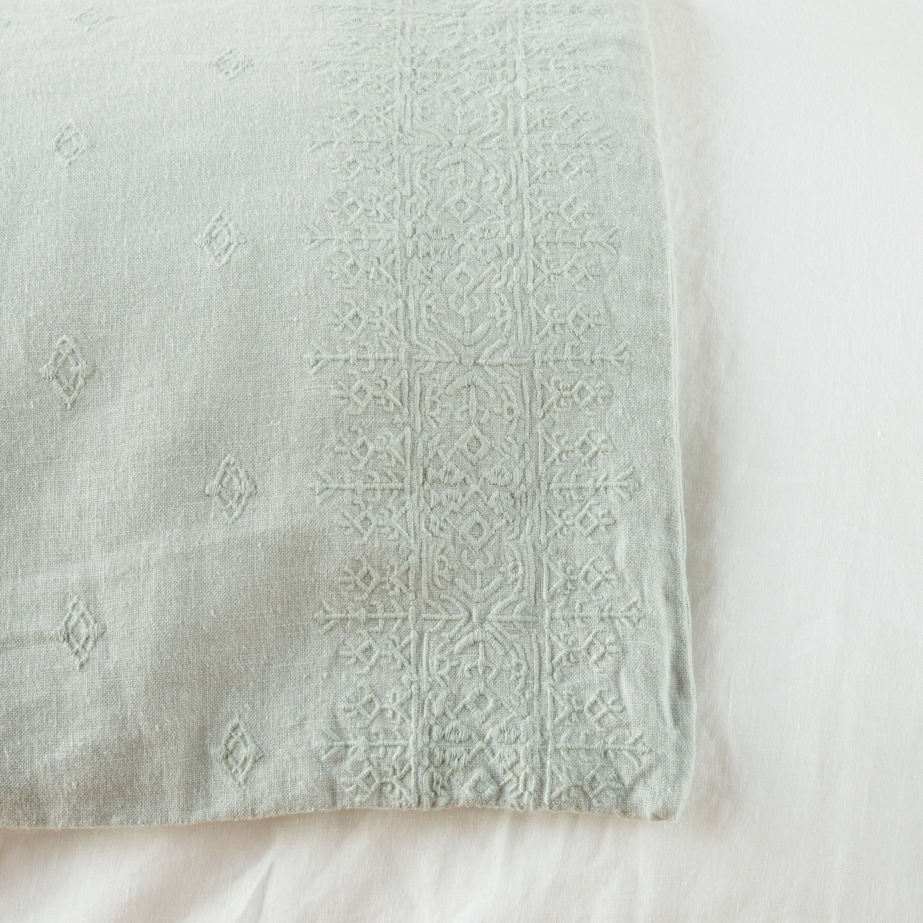 Eucalyptus: Close-up of corner against a white background, showcasing embroidery pattern detail - overhead view.