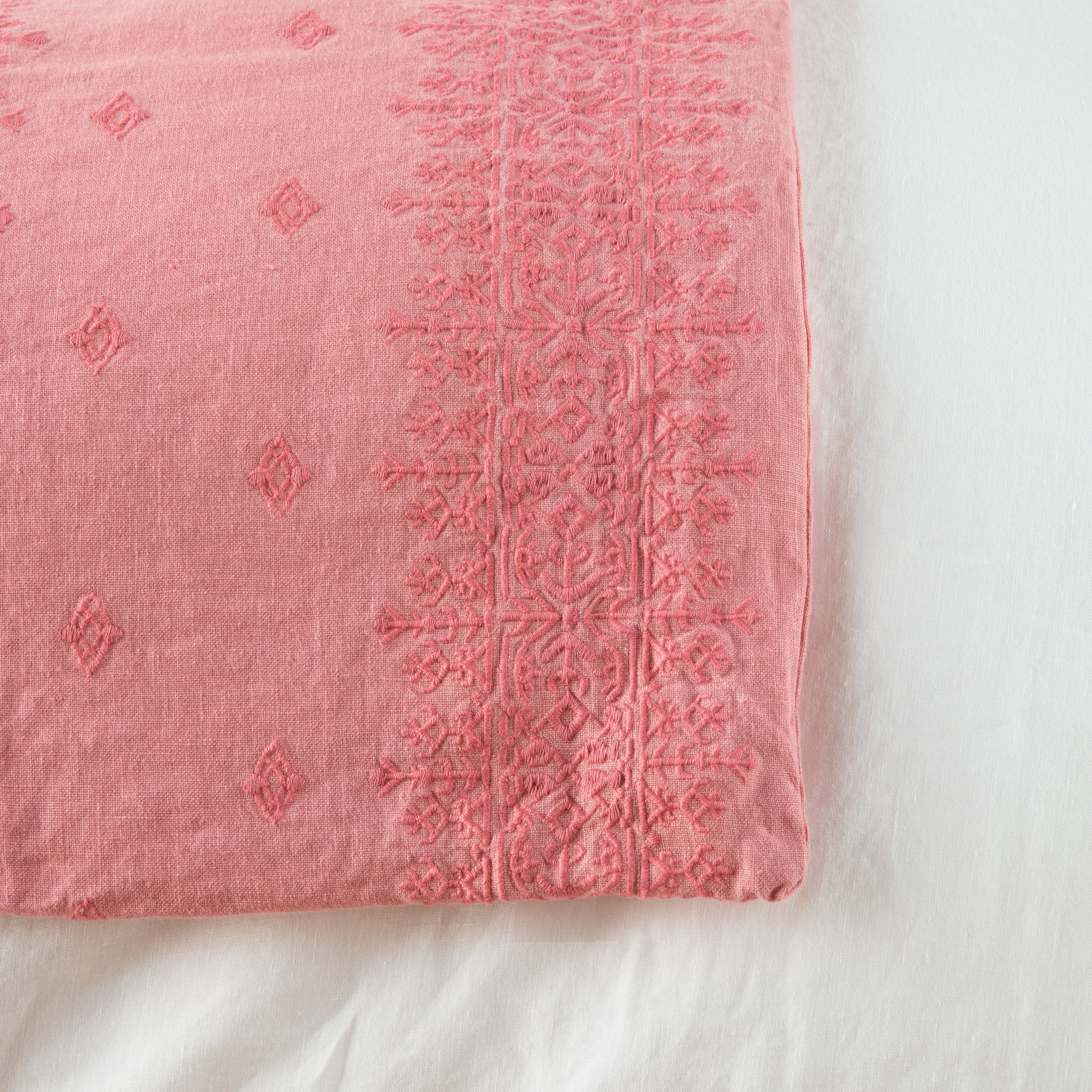 Poppy: Close-up of corner against a white background, showcasing embroidery pattern detail - overhead view.
