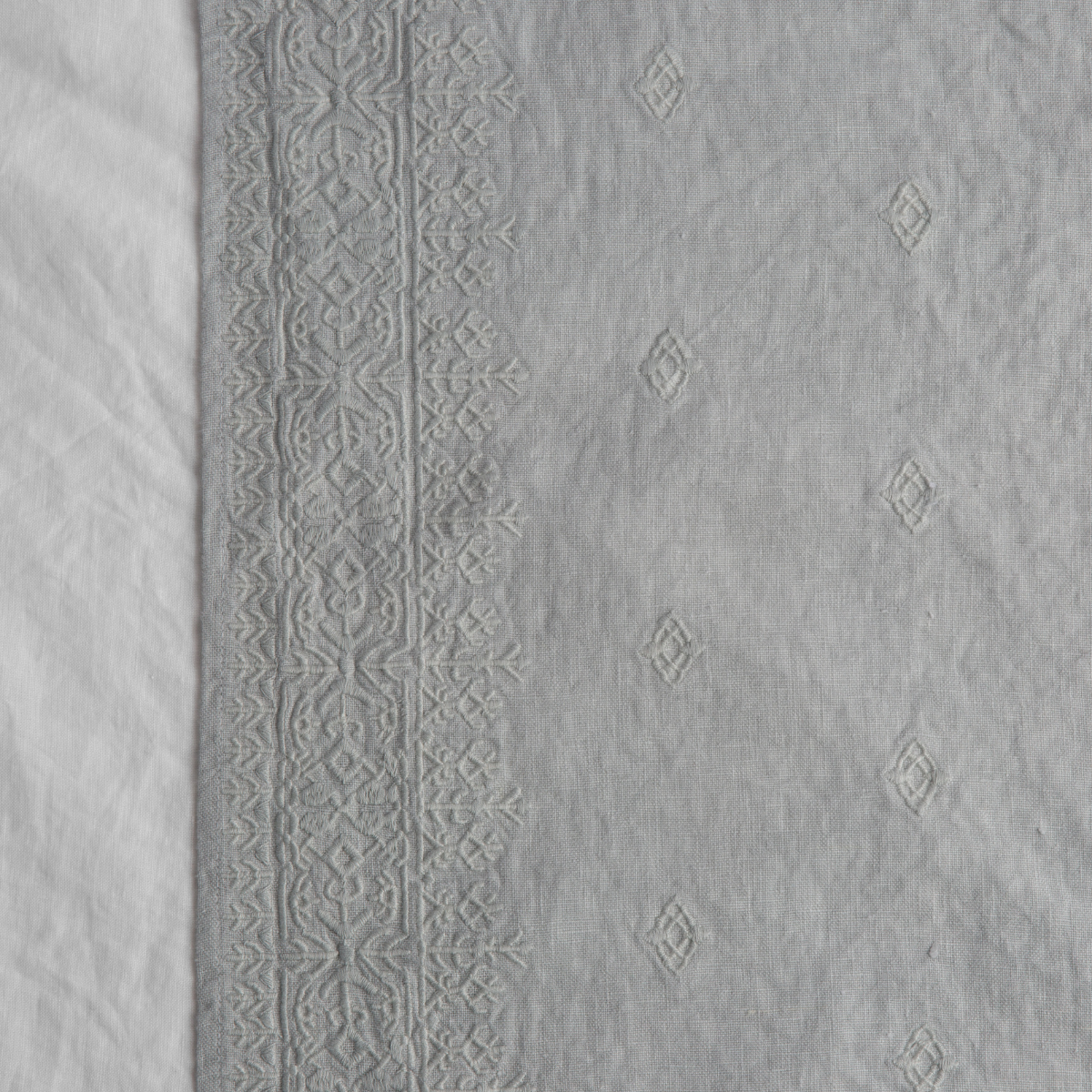 Cloud: A close up of Ines, midweight linen with cotton embroidery, in eucalyptus, a soft light green. 