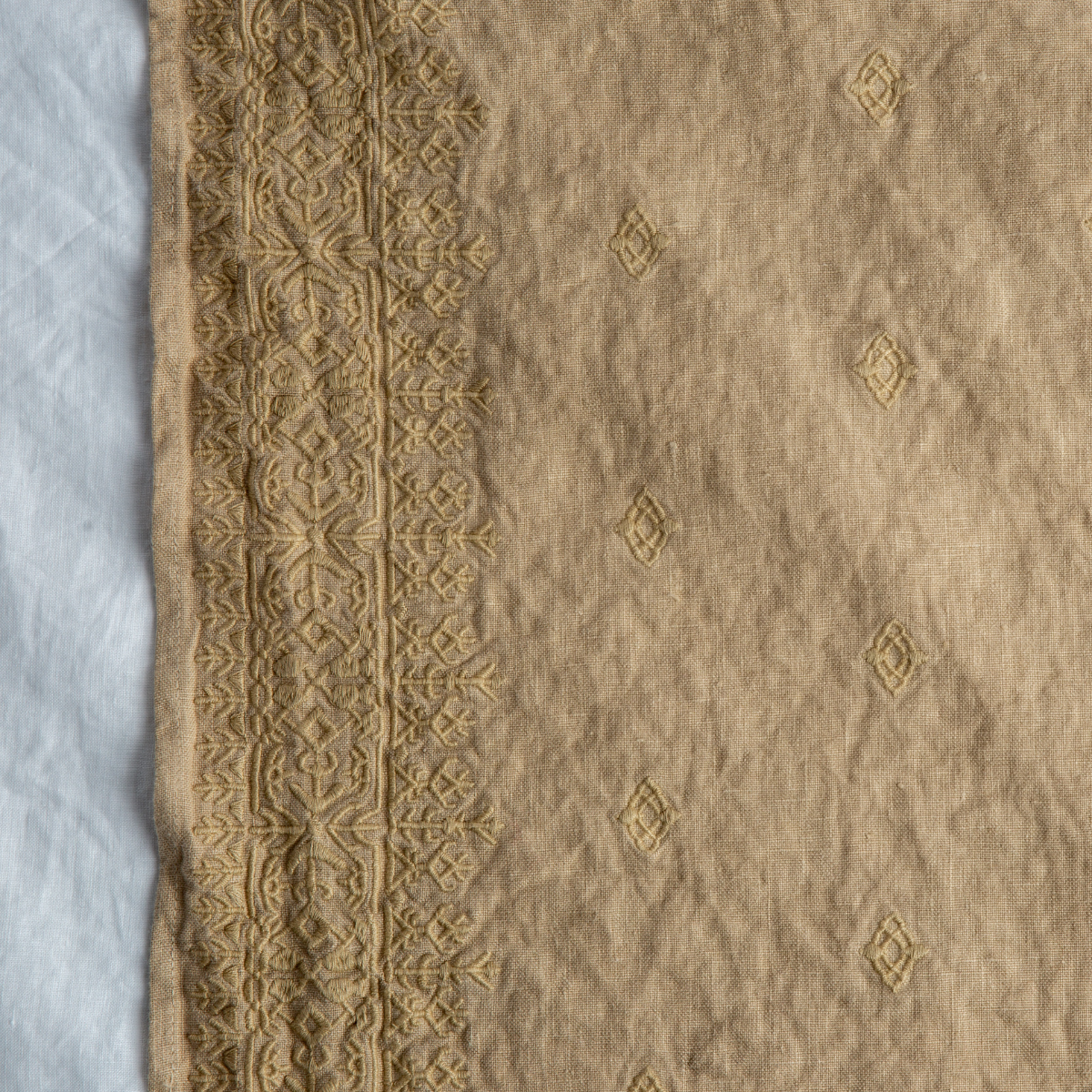 Honeycomb: A close up of Ines, midweight linen with cotton embroidery, in honeycomb, a warm golden tone.