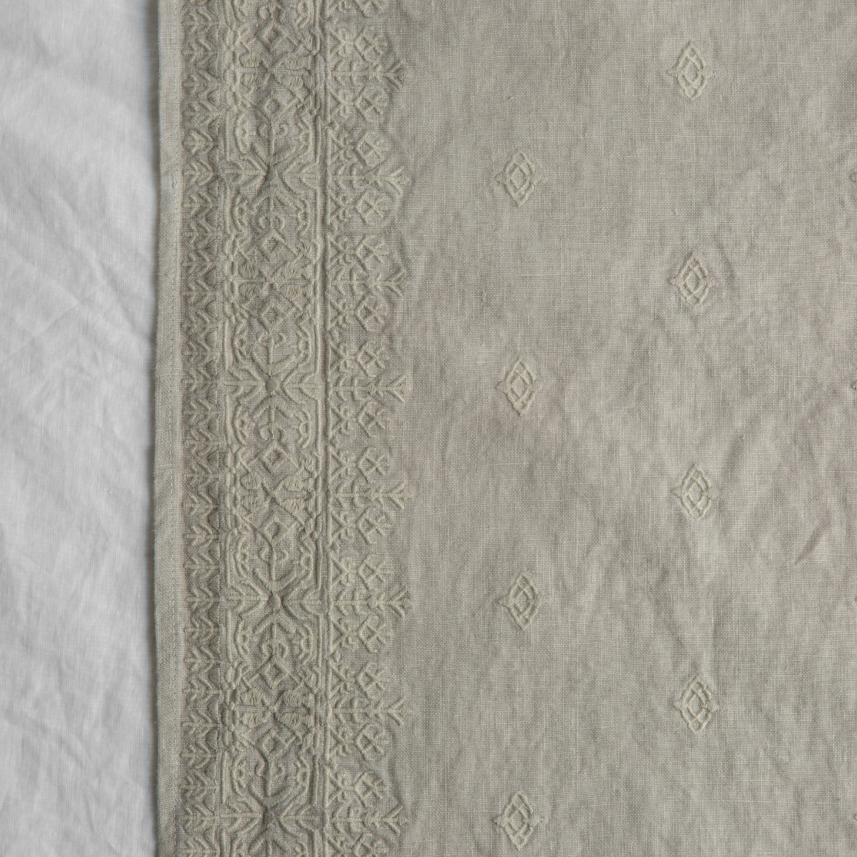 Sterling: A close up of Ines, midweight linen with cotton embroidery, in white.