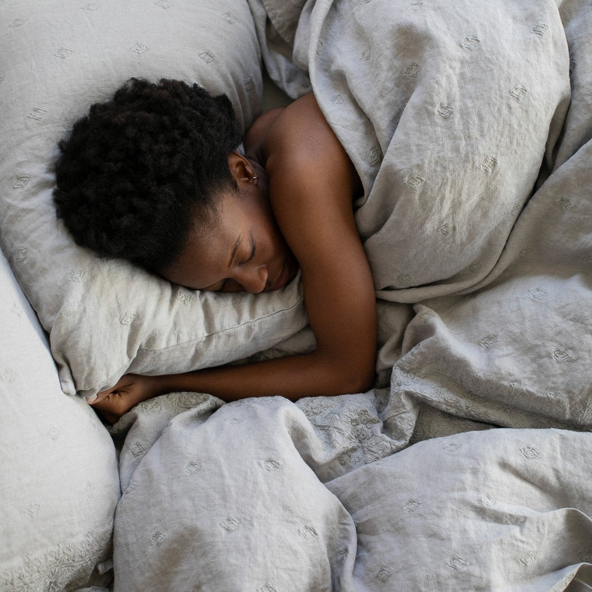 : Woman sleeping under Ines duvet in fog - overhead view.