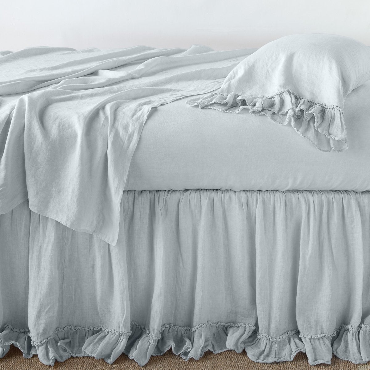 Cloud: bed skirt layered with monochromatic linen sheeting - side view.