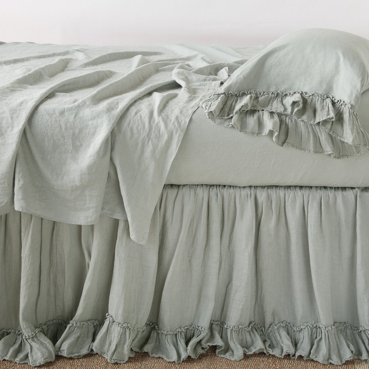 Eucalyptus: bed skirt layered with monochromatic linen sheeting - side view.