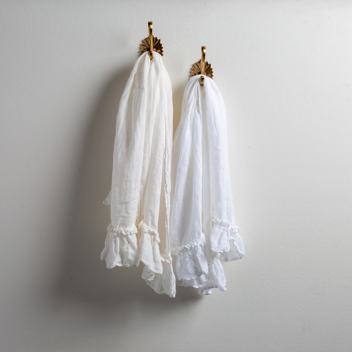 [allvariants]: Two Linen Whisper guest towels, draped over decorative hooks against a white wall - white and winter white.