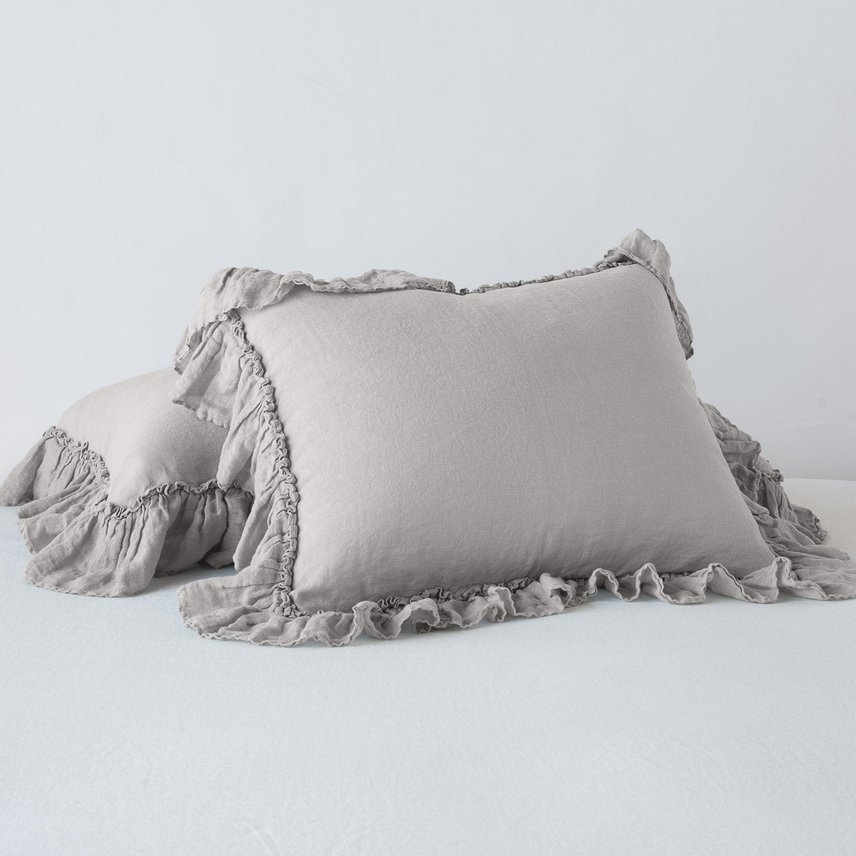 Fog: standard sham leaning against a king sham laying flat, on a plain background.