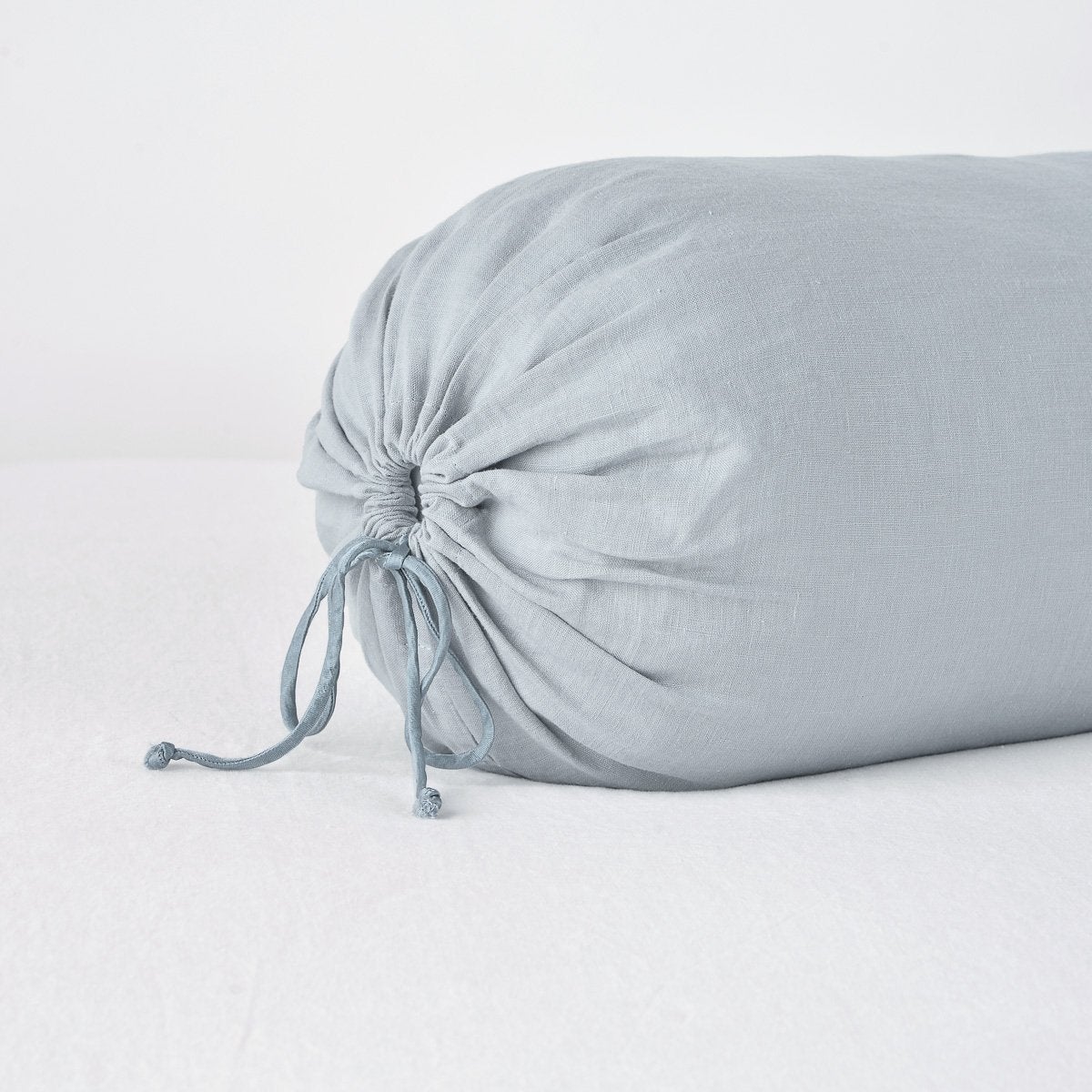 Mineral: Close-up of Linen bolster end detail in mineral, angled to show gathering and satin ties.