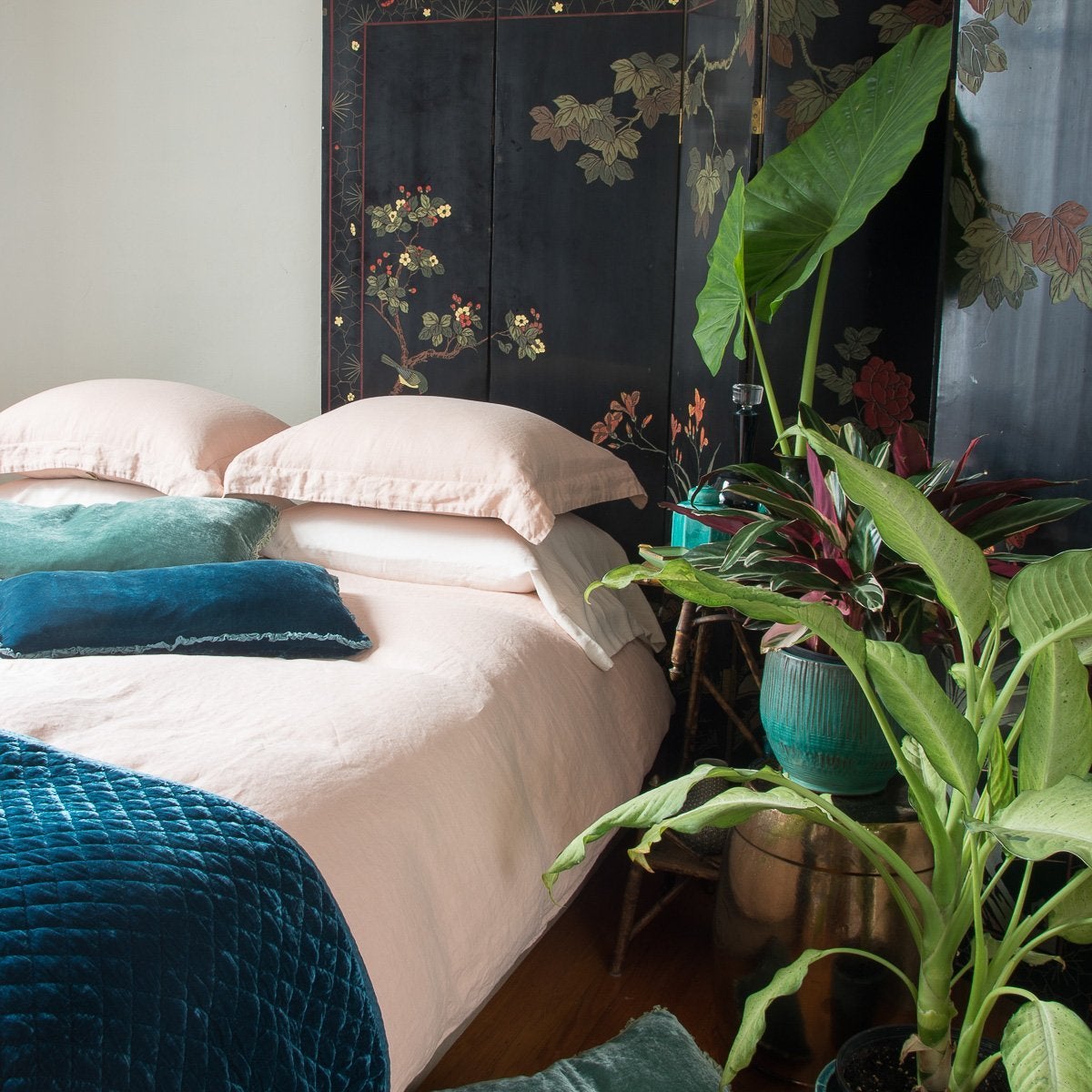 [allvariants]: Linen duvet cover in pearl on a neatly made bed. Silk velvet accents in blues and greens are complemented by on-tone ceramics, dark floral wall panel, and tall greenery - cropped three-quarter angle.