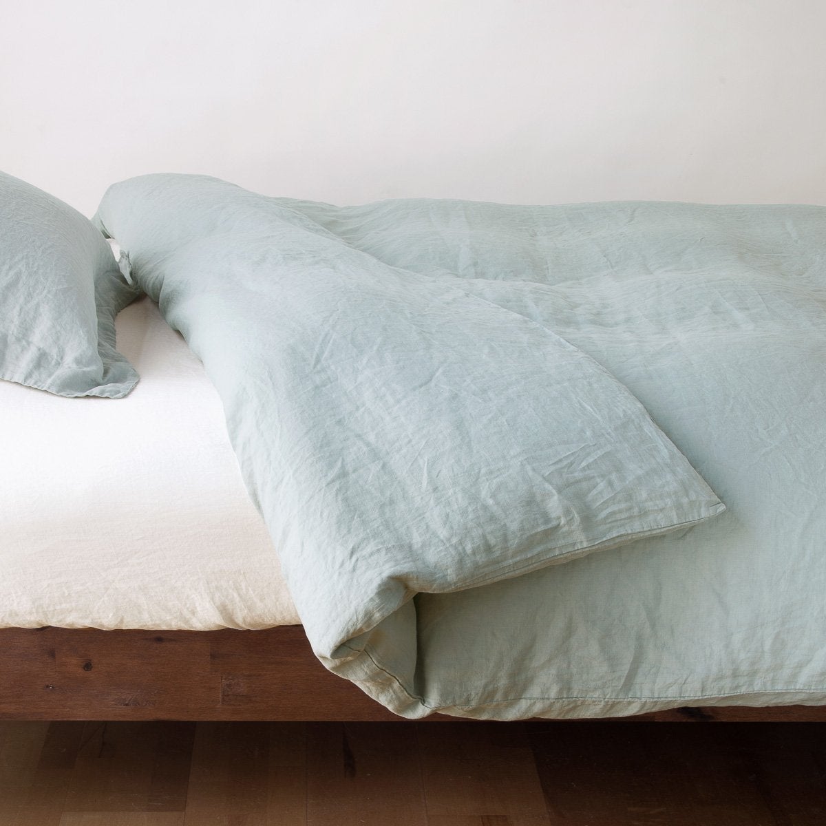 Eucalyptus: duvet cover neatly folded back over white linen sheeting - side view.