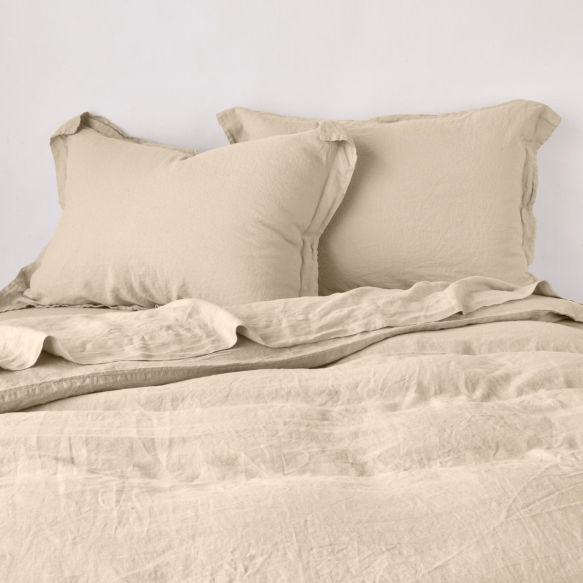 Honeycomb: duvet cover partially folded back on a bed with matching sheets and shams against a white wall - cropped end of bed view.
