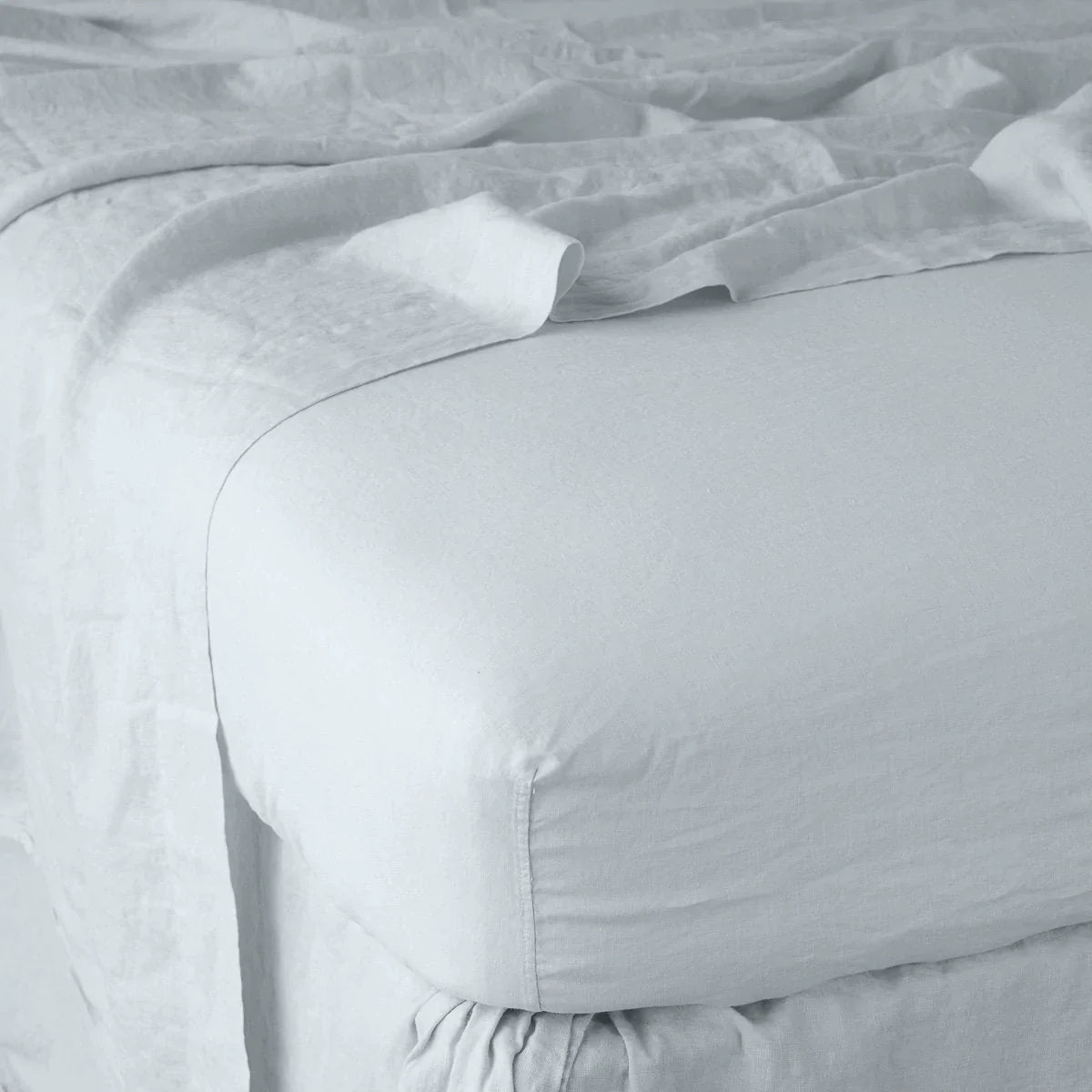 Cloud: close up of fitted sheet with matching rumpled flat sheet - corner view.