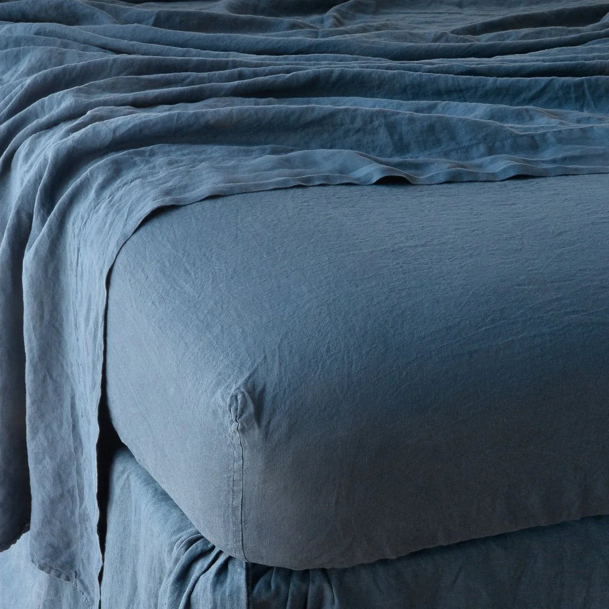 Midnight: close up of fitted sheet with matching rumpled flat sheet - corner view.