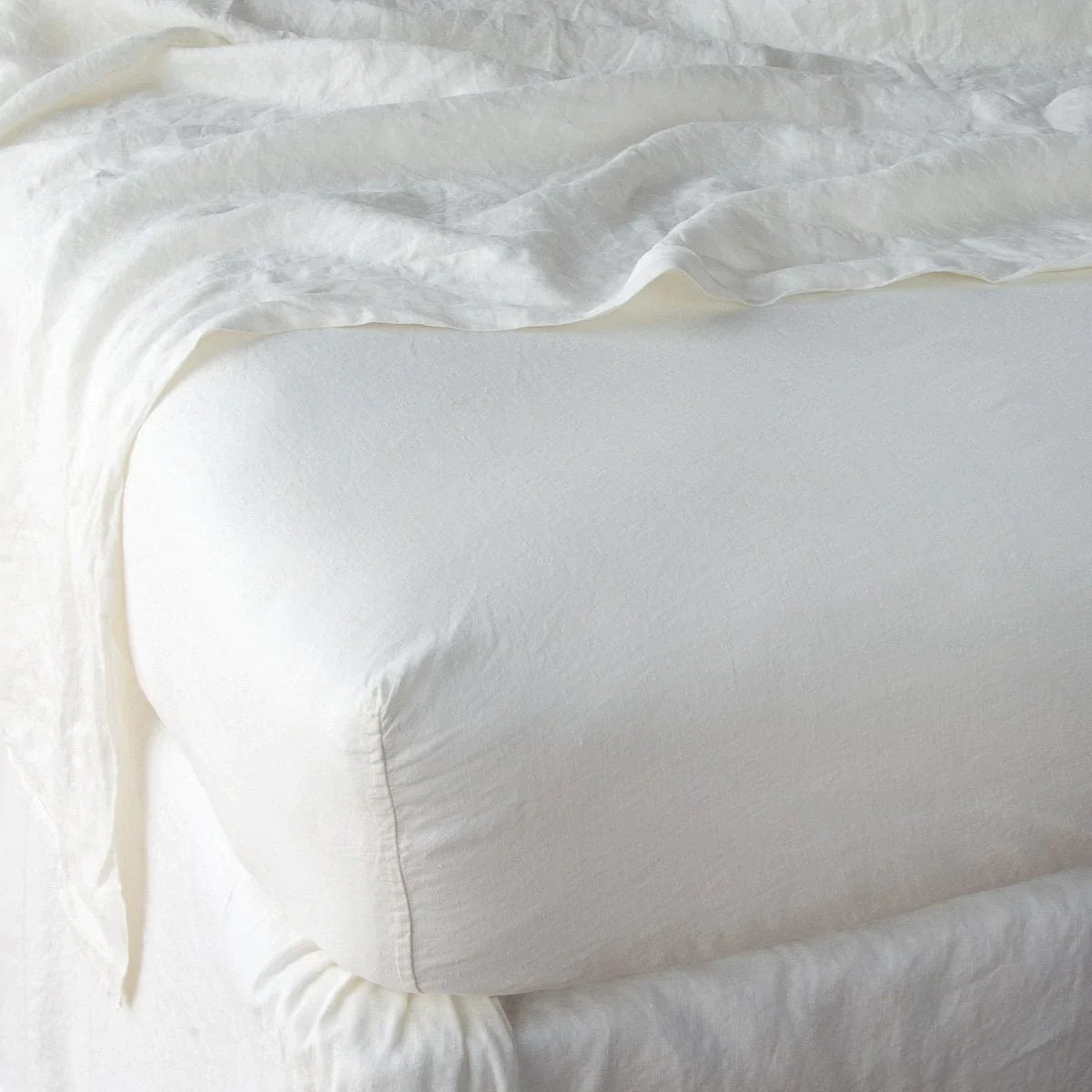Winter White: close up of fitted sheet with matching rumpled flat sheet - corner view.