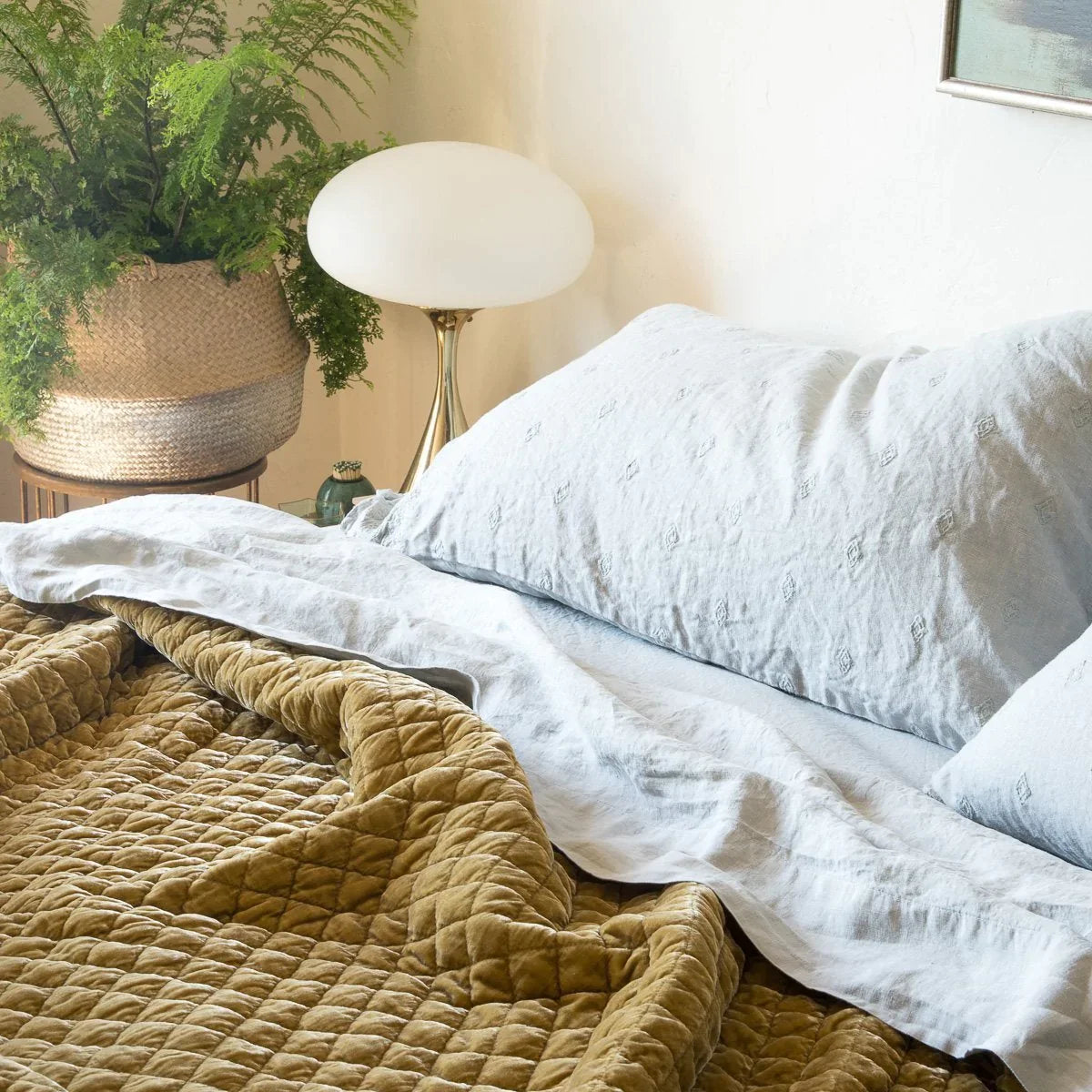 [allvariants]: Soft linen sheeting in cloud, layered with contrasting textures of embroidered linen and rich gold tones of quilted silk velvet. - close-up three-quarter view.