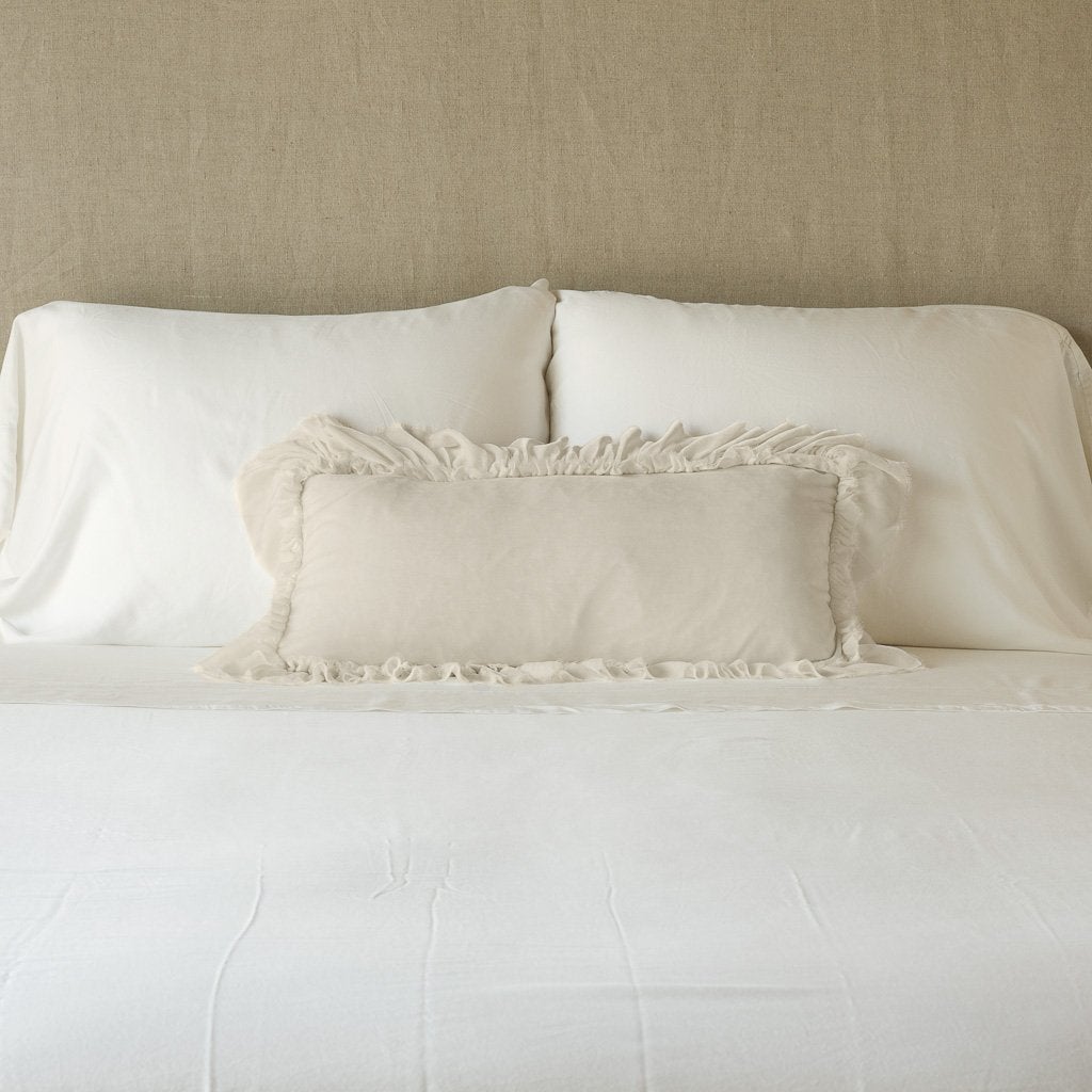 Parchment: pillow on a white bed - cropped end of bed view.