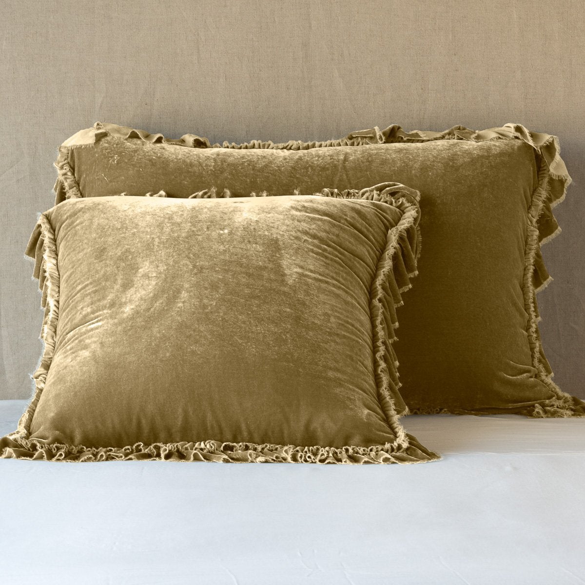 Honeycomb: shams leaning upright on white sheets against a neutral headboard.
