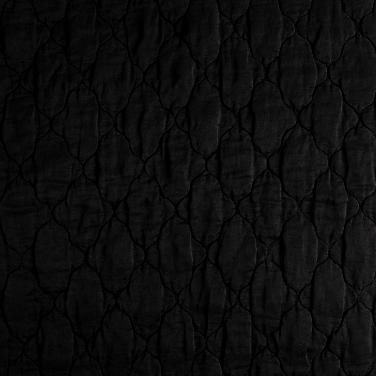Corvino: A close up of quilted charmeuse fabric in Corvino, a black tone