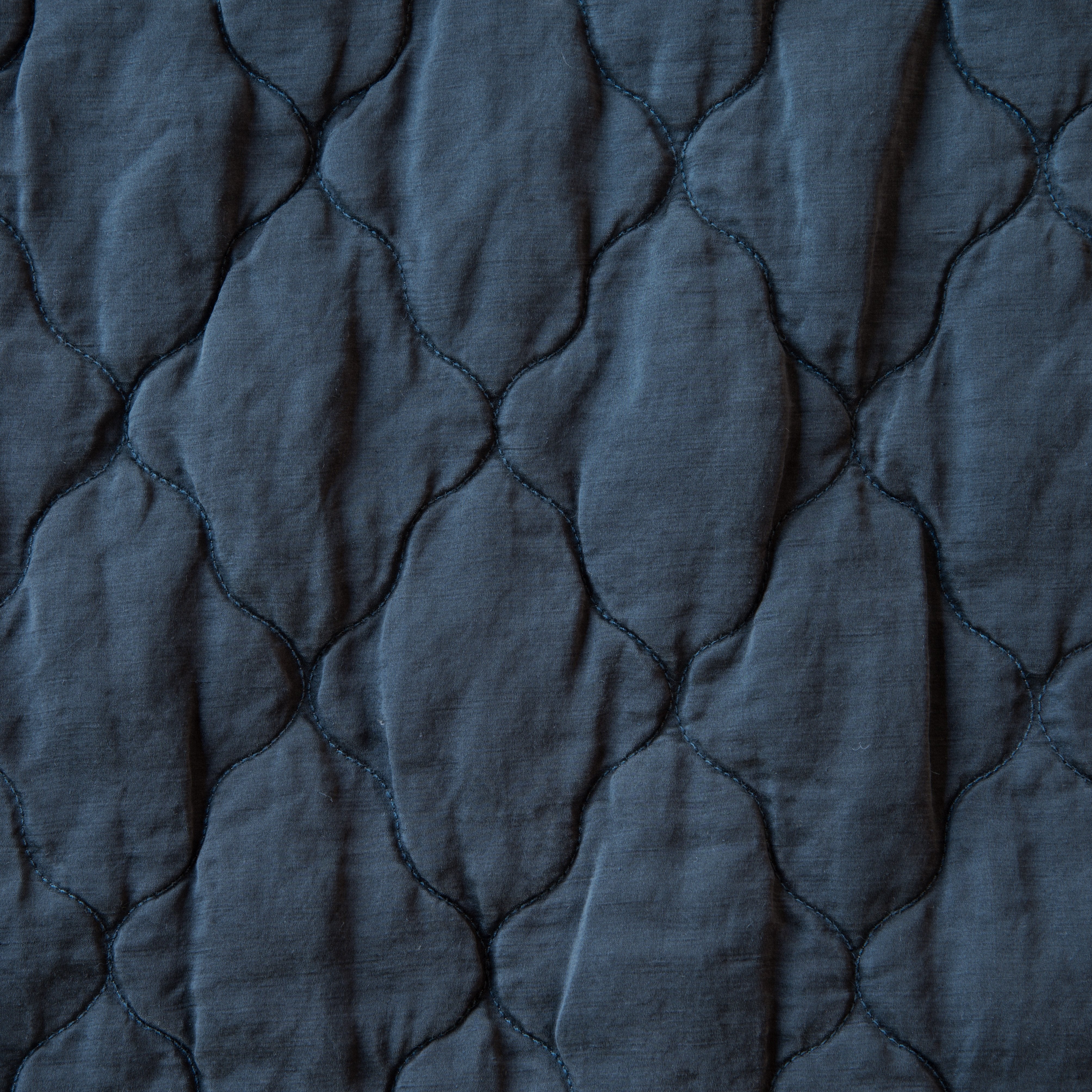 Midnight: Close-up of Luna silk charmeuse quilting in midnight, a rich indigo tone. 