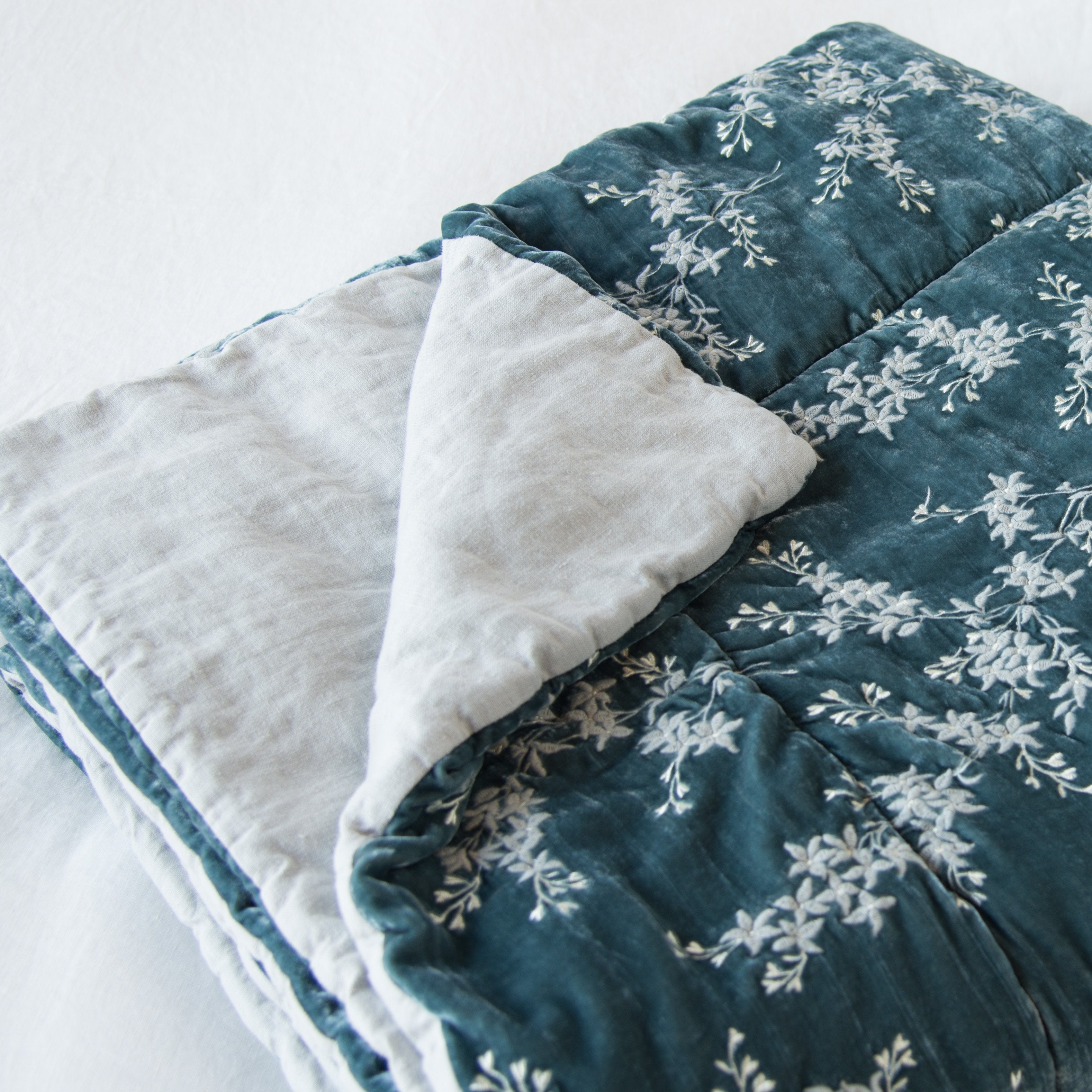 [allvariants]: Lynette throw blanket in mineral, neatly folded on a light background, with a corner turned back to  showcase the linen back - slight overhead angle.