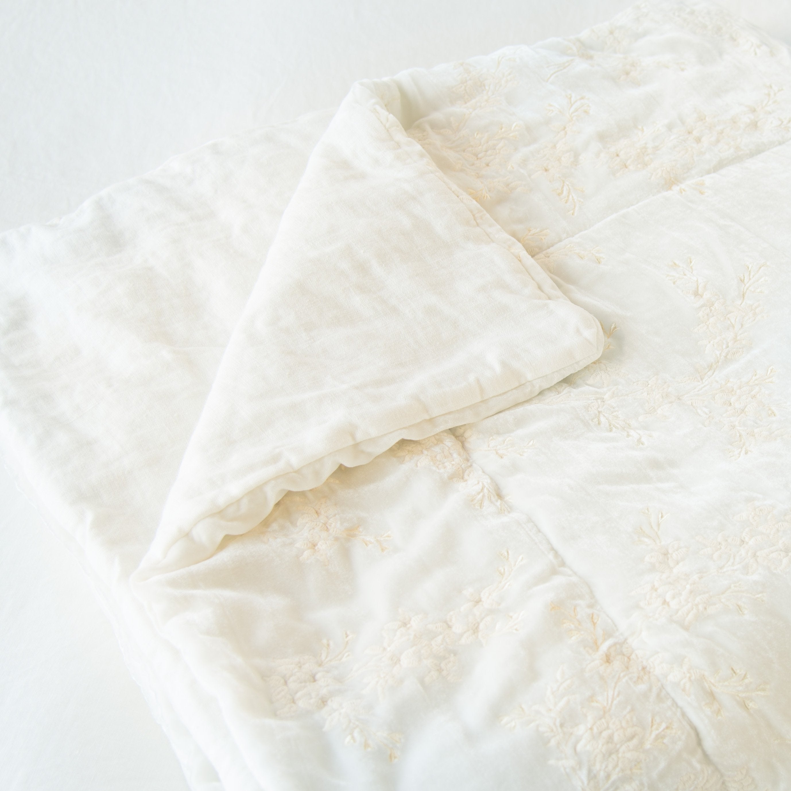 Winter White: Close up of blanket neatly folded on a light background, with a corner turned back to  showcase the linen back - slight overhead angle.