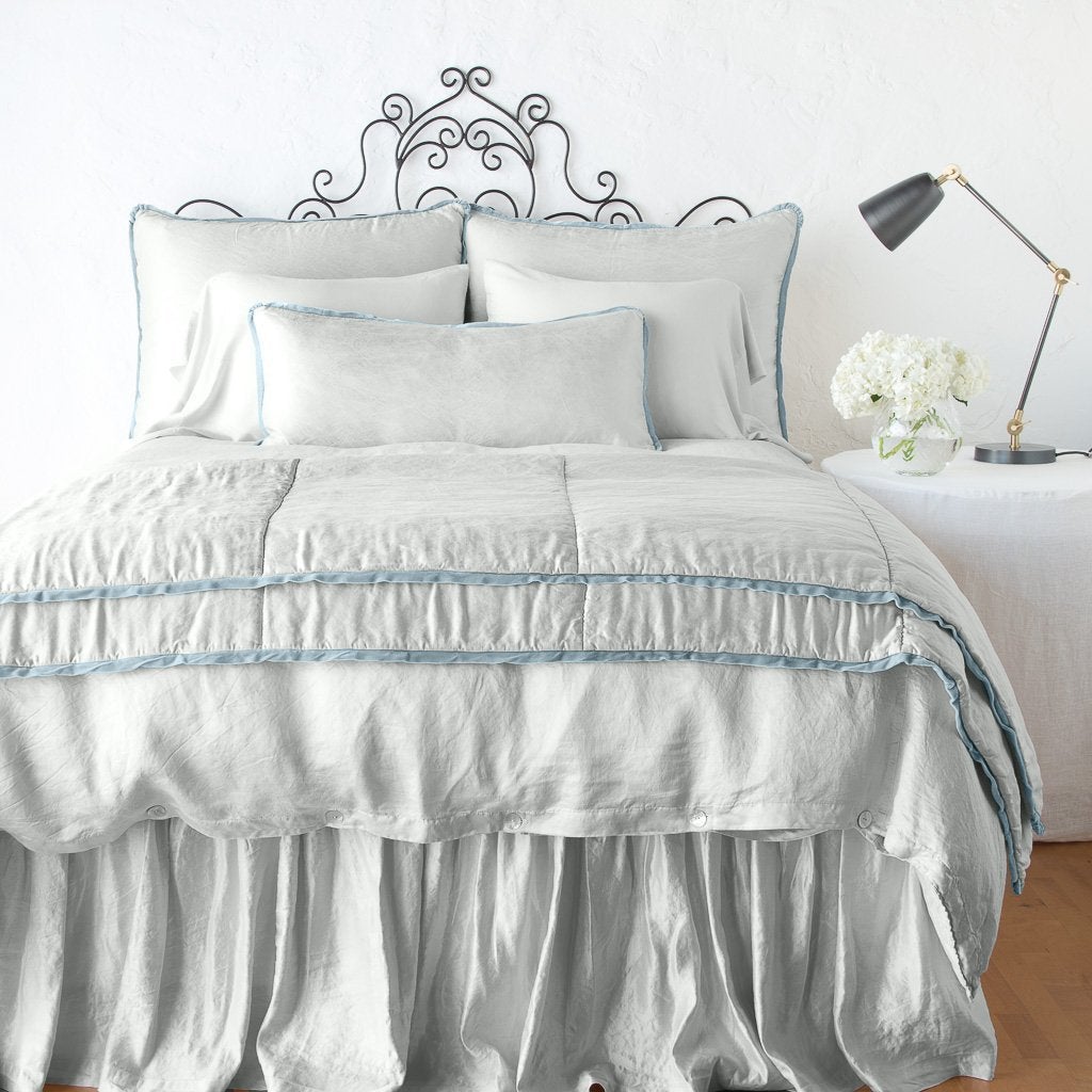 Cloud: throw blanket folded at the end of a monochromatic, charmeuse bed - end of bed view.