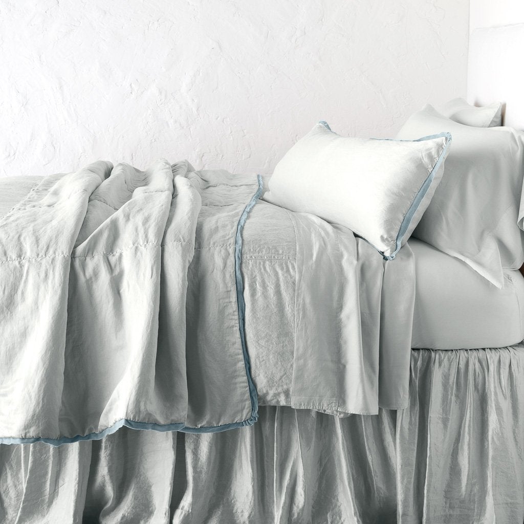 Cloud: throw blanket rumpled on a charmeuse monochromatic bed - side view.