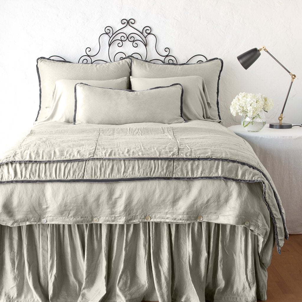 Fog: throw blanket folded at the end of a monochromatic, charmeuse bed - end of bed view.