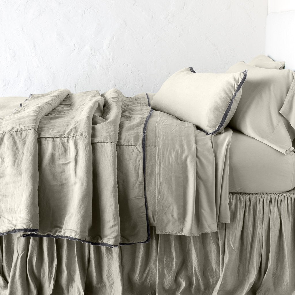 Fog: throw blanket rumpled on a charmeuse monochromatic bed - side view.