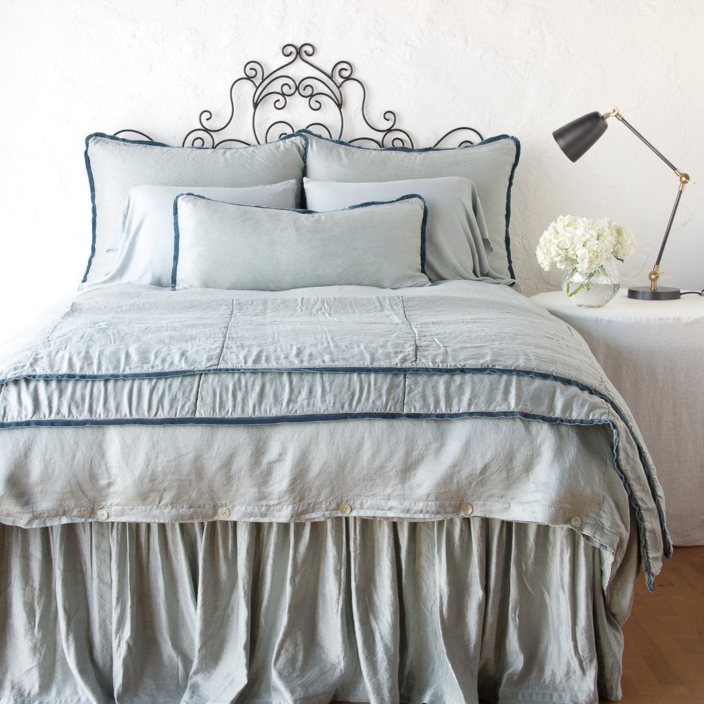 Mineral: throw blanket folded at the end of a monochromatic, charmeuse bed - end of bed view.