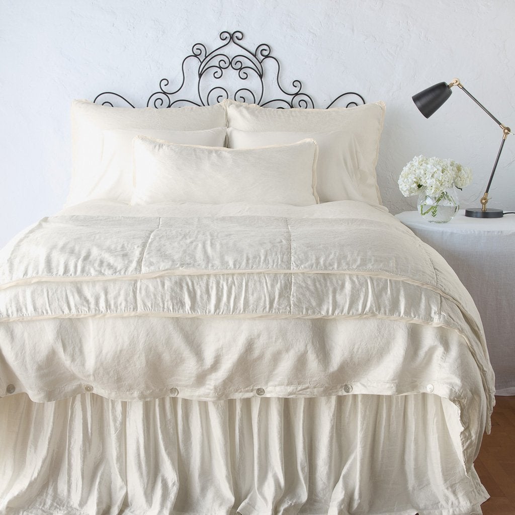 Parchment: throw blanket folded at the end of a monochromatic, charmeuse bed - end of bed view.
