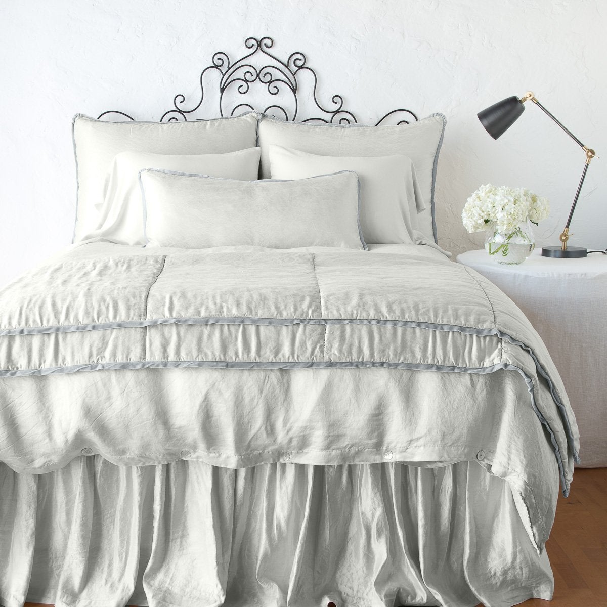 Sterling: throw blanket folded at the end of a monochromatic, charmeuse bed - end of bed view.