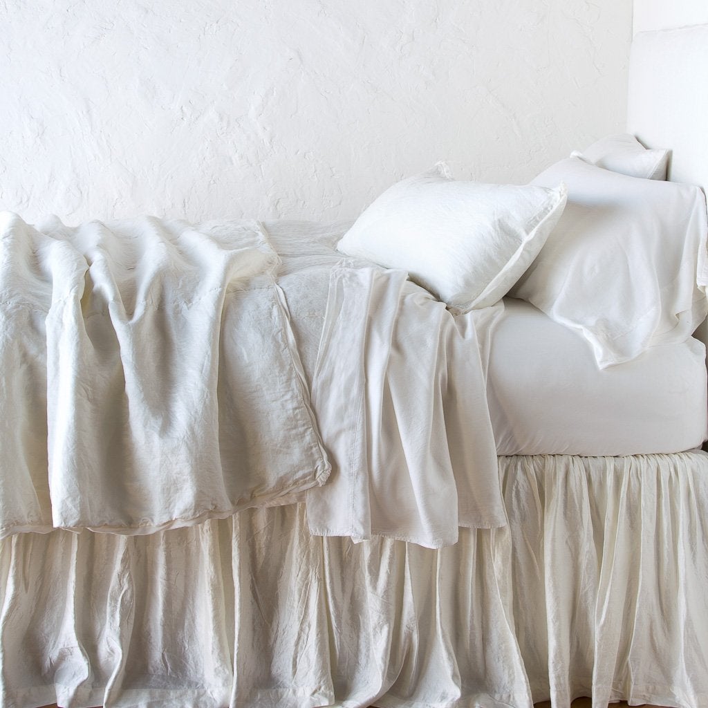 Winter White: throw blanket rumpled on a charmeuse monochromatic bed - side view.