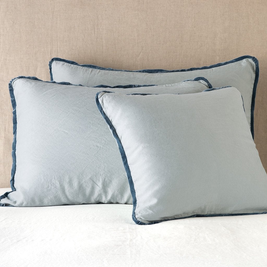 Mineral: shams leaning upright on white sheeting against a neutral headboard.