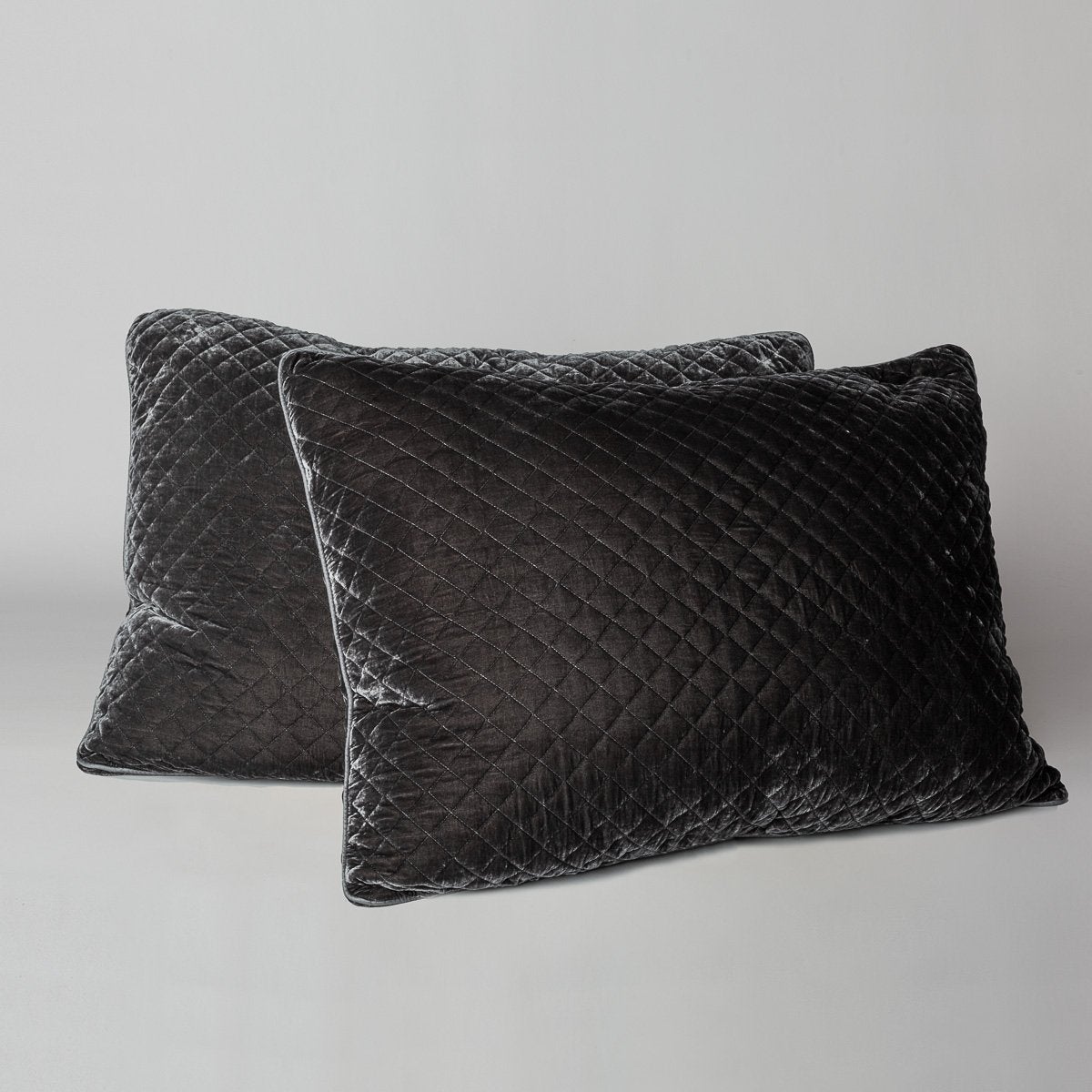 Moonlight: shams leaning upright against a neutral headboard. One sham is backwards to showcase the shimmering shell button closure.