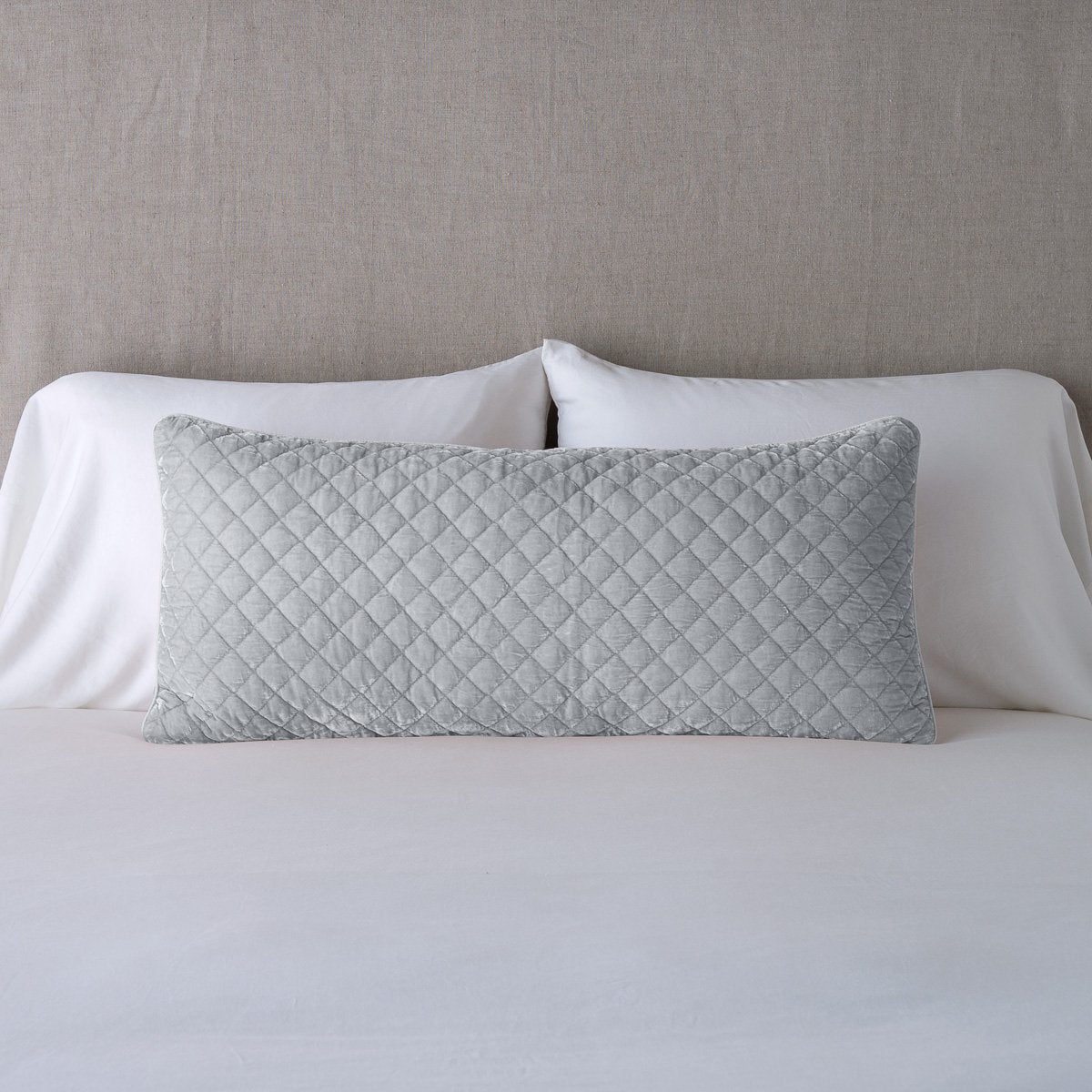 Sterling: 16x36 pillow leaning upright against white sleeping pillows and a neutral headboard.