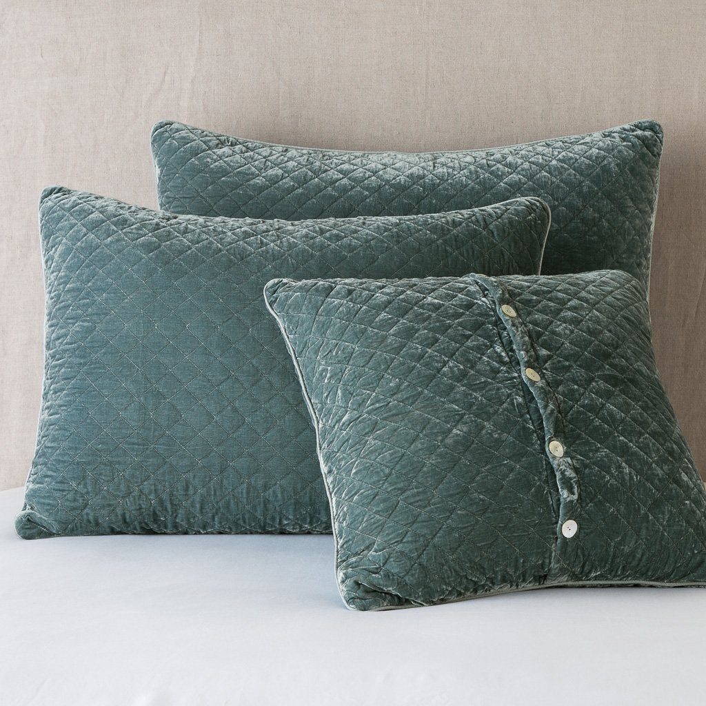 Eucalyptus: shams leaning upright against a neutral headboard. One sham is backwards to showcase the shimmering shell button closure.