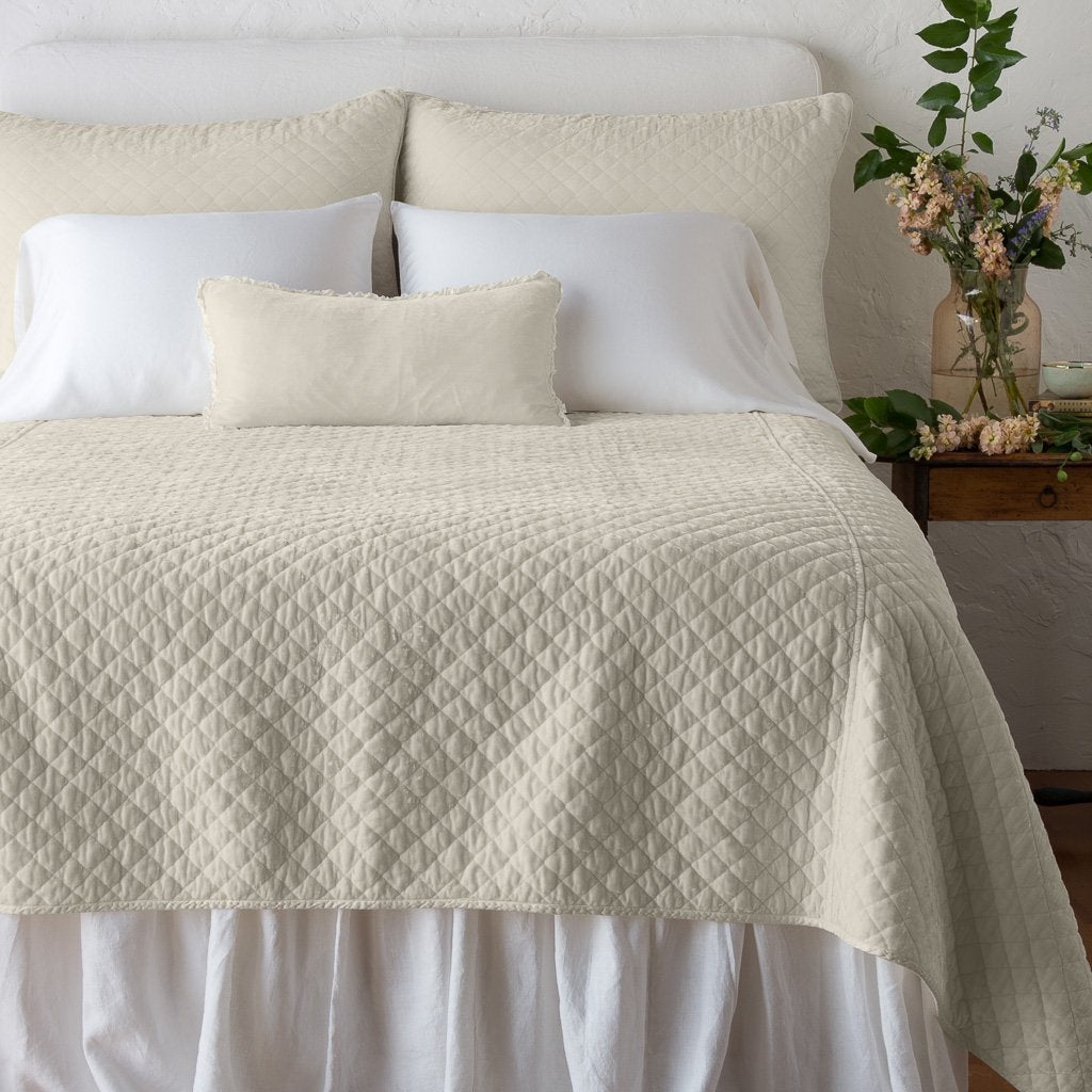 Parchment: shams with matching coverlet on a neatly-made, bed with white sheeting - end of bed view.