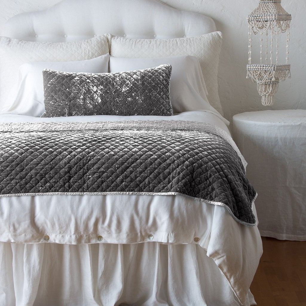 Fog: throw blanket and matching lumbar pillow on a neatly made white bed - end of bed view.