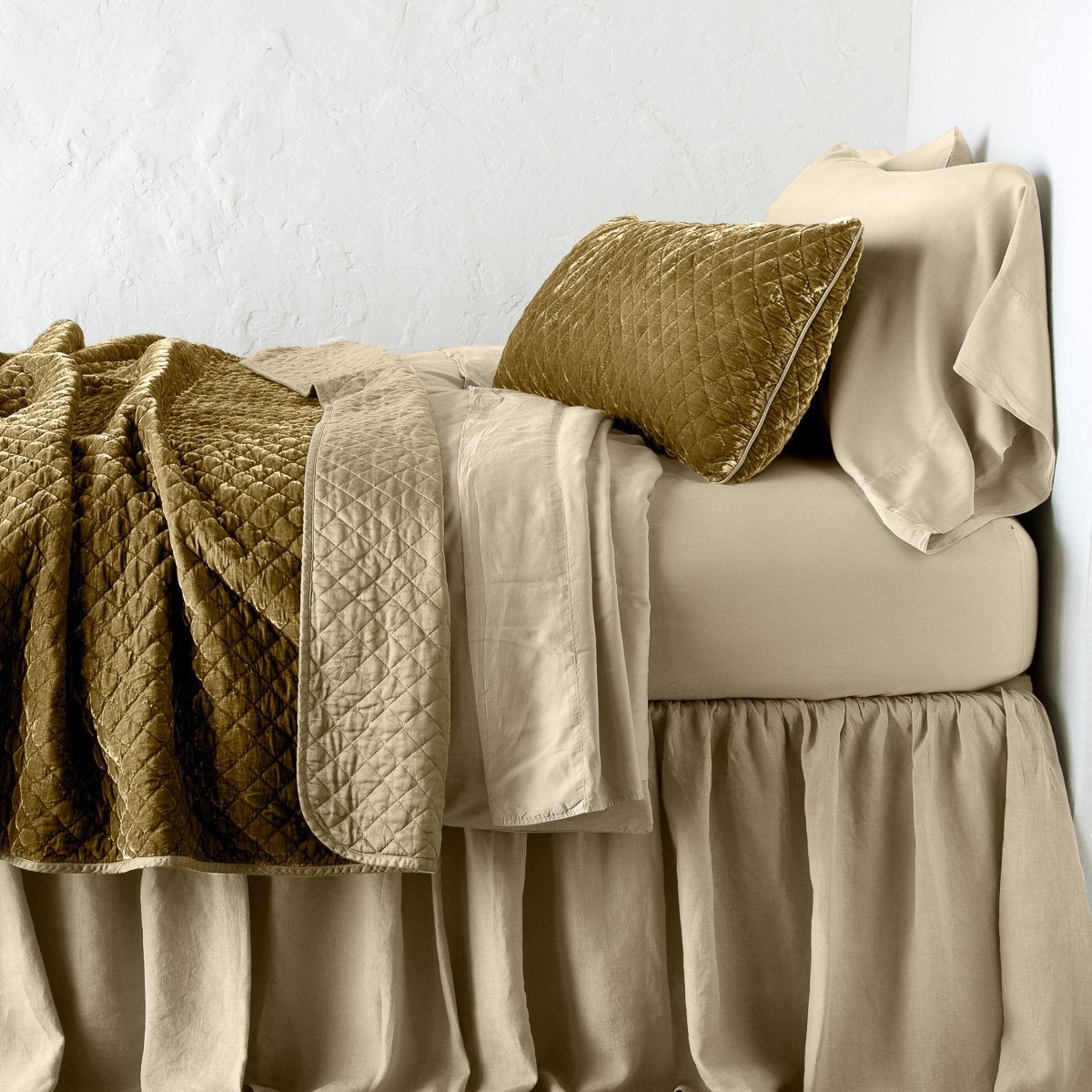 Honeycomb: throw blanket rumpled and folded back, featuring satin back. Shown with matching lumbar pillow and monochromatic sheeting - side view.