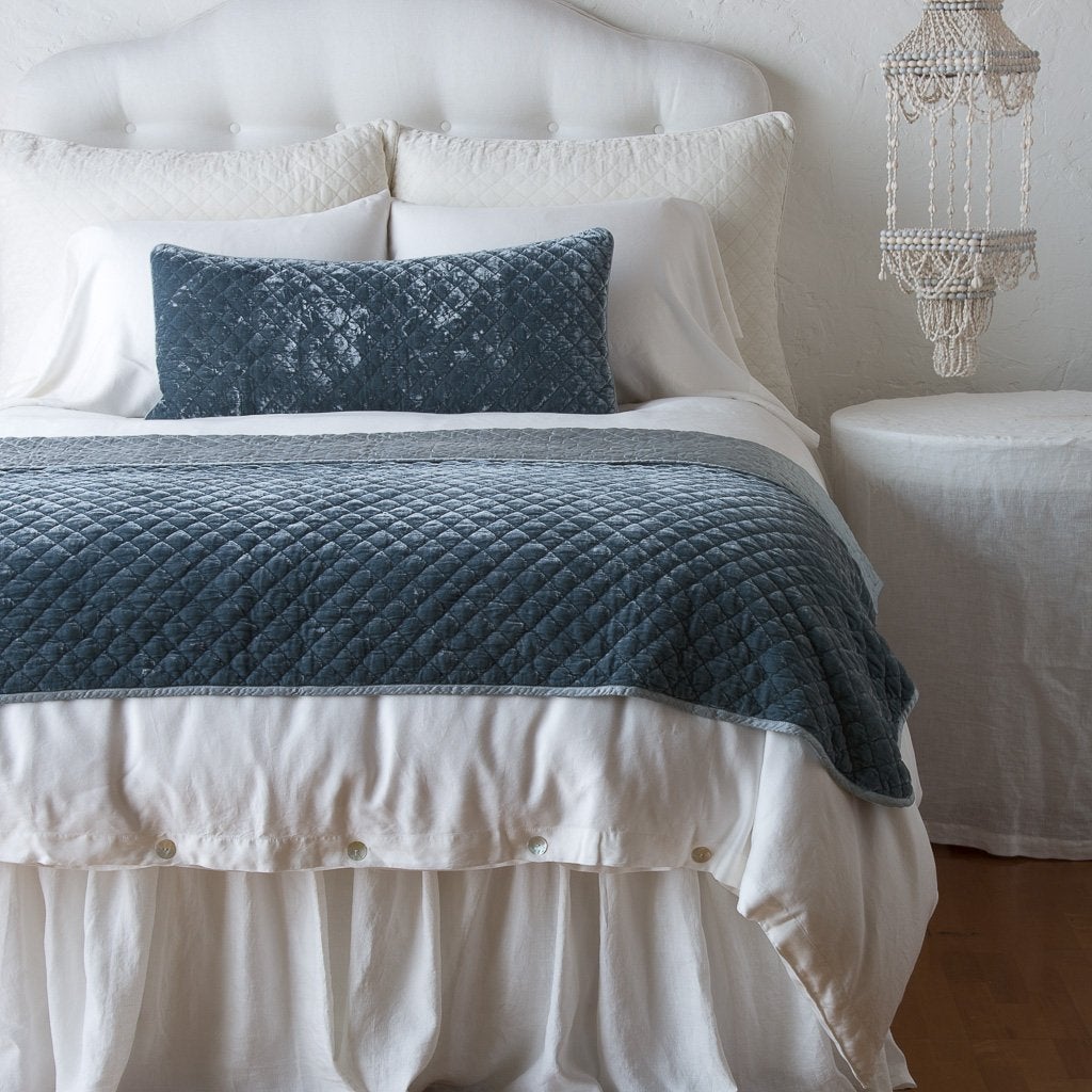 Mineral: throw blanket and matching lumbar pillow on a neatly made white bed - end of bed view.
