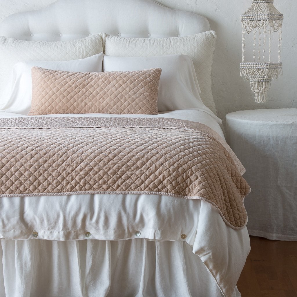 Pearl: throw blanket and matching lumbar pillow on a neatly made white bed - end of bed view.