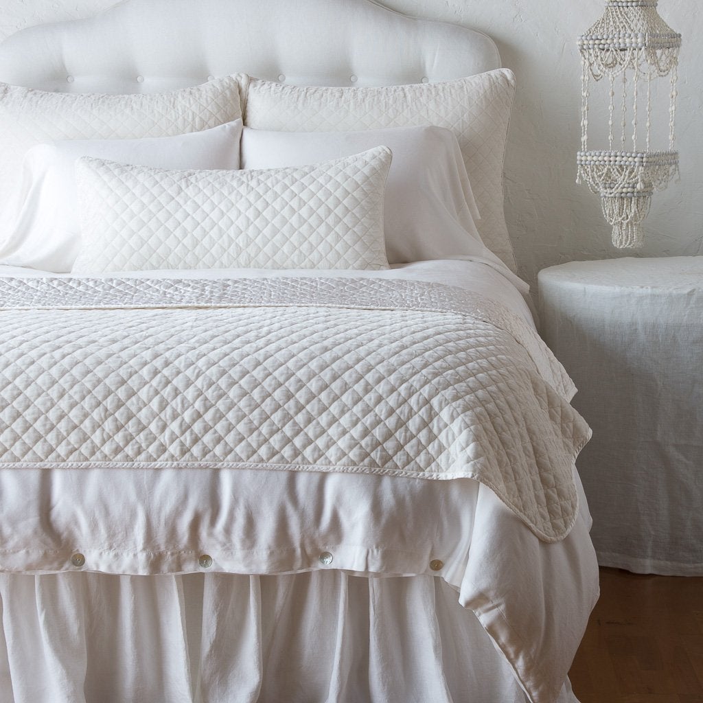 Winter White: throw blanket and matching lumbar pillow on a neatly made white bed - end of bed view.