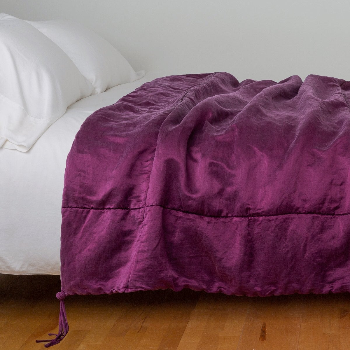 : blanket draped over a white bed - side view.