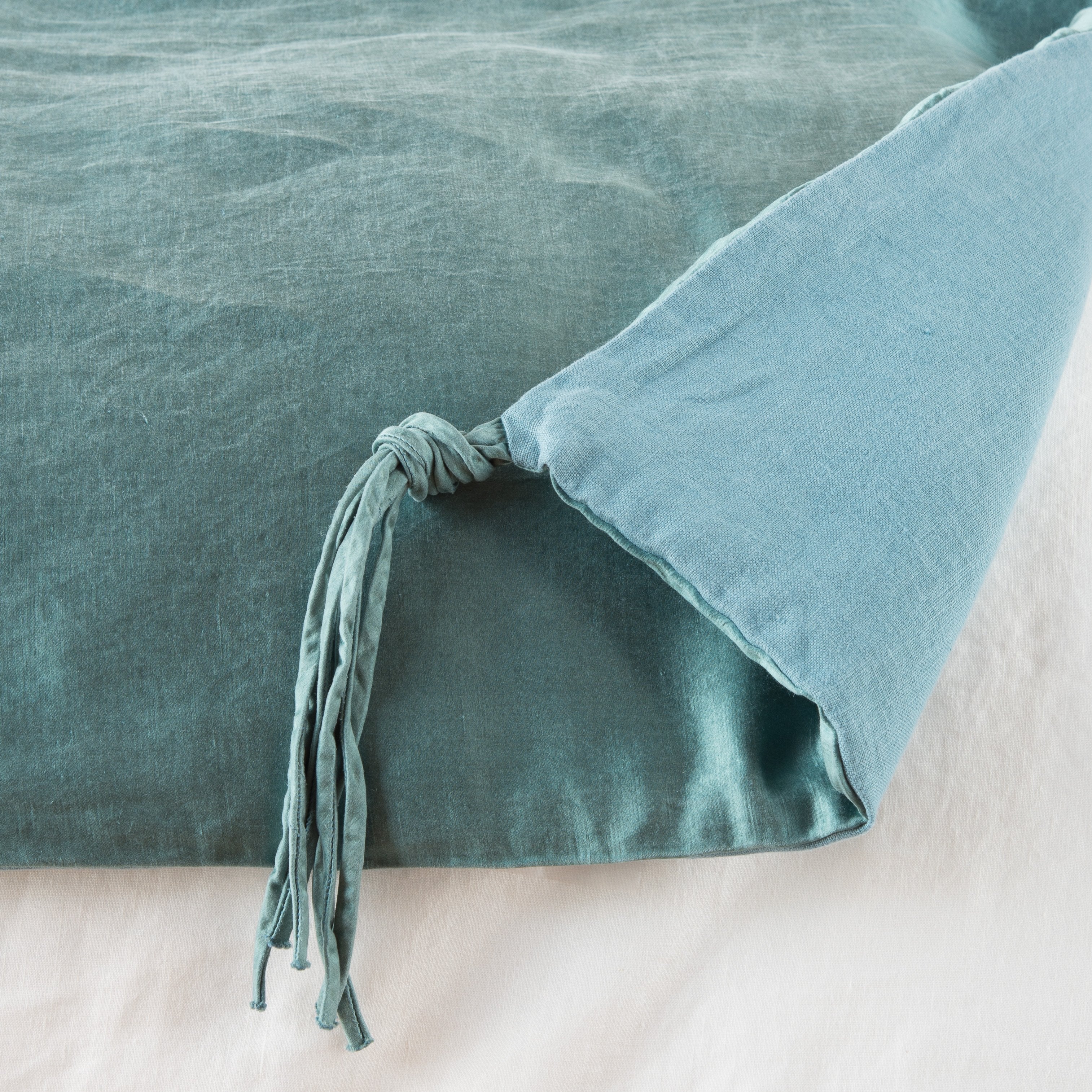Cenote: Close up of blanket, with a corner turned back to showcase the midweight linen back and corner tassel - overhead view.