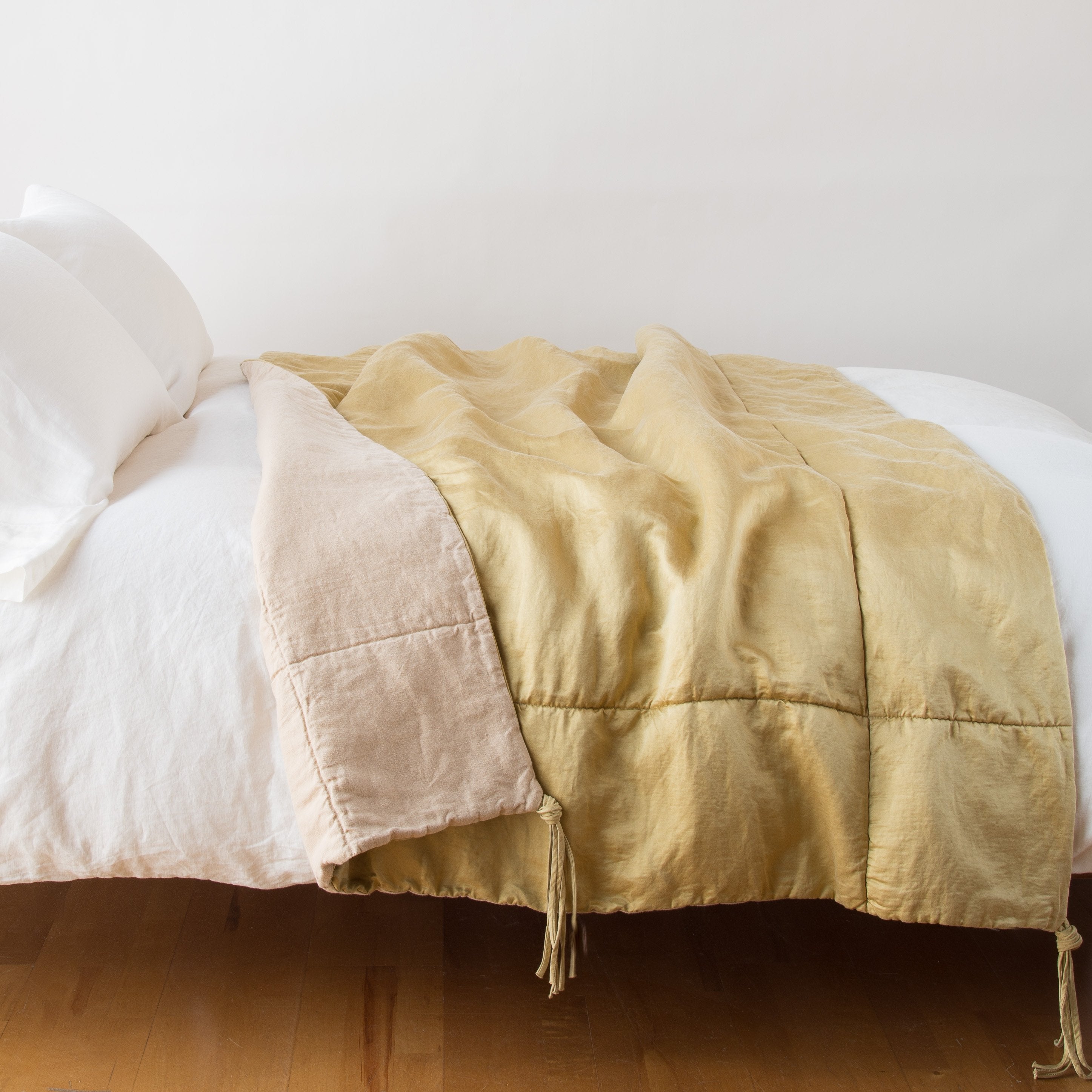 Honeycomb: blanket draped over a white bed, folded back to reveal midweight linen back - side view.